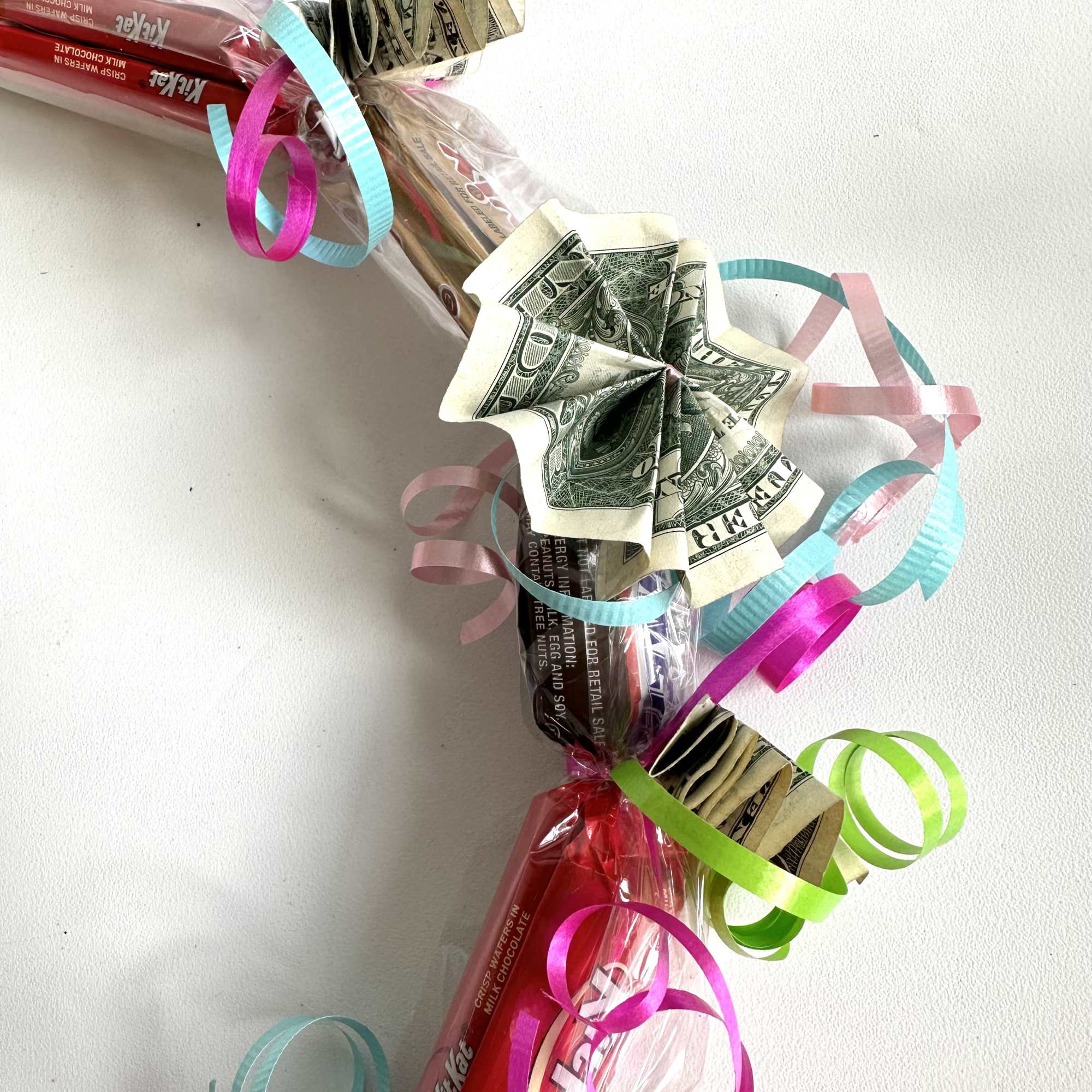 Candy bars wrapped with colorful ribbons and folded dollar bills