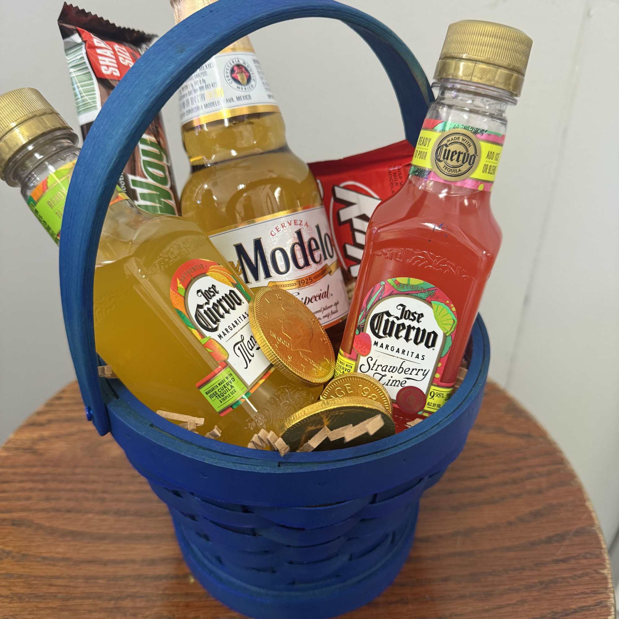 Bright blue woven basket packed with miniature liquor bottles, candy bars, and