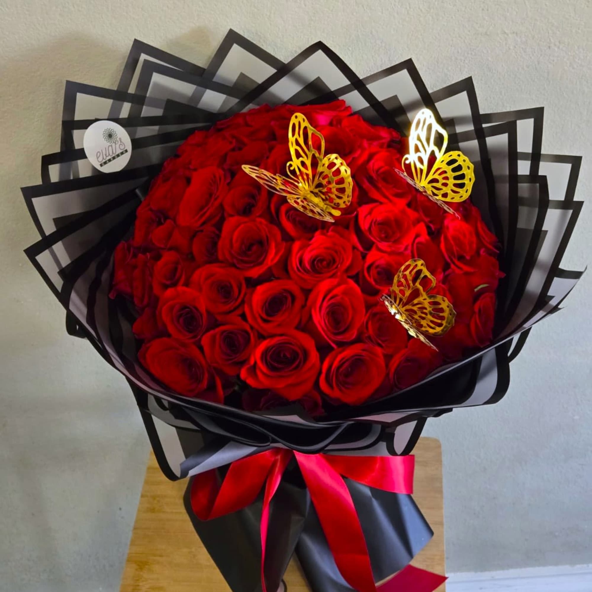 Bouquet of red roses wrapped in black paper with butterfly decorations