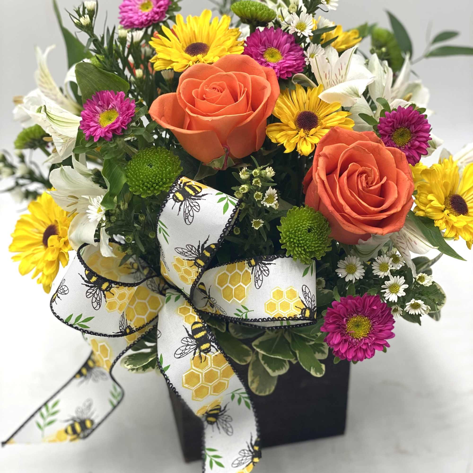 Orange roses with yellow and purple daisies in a black box