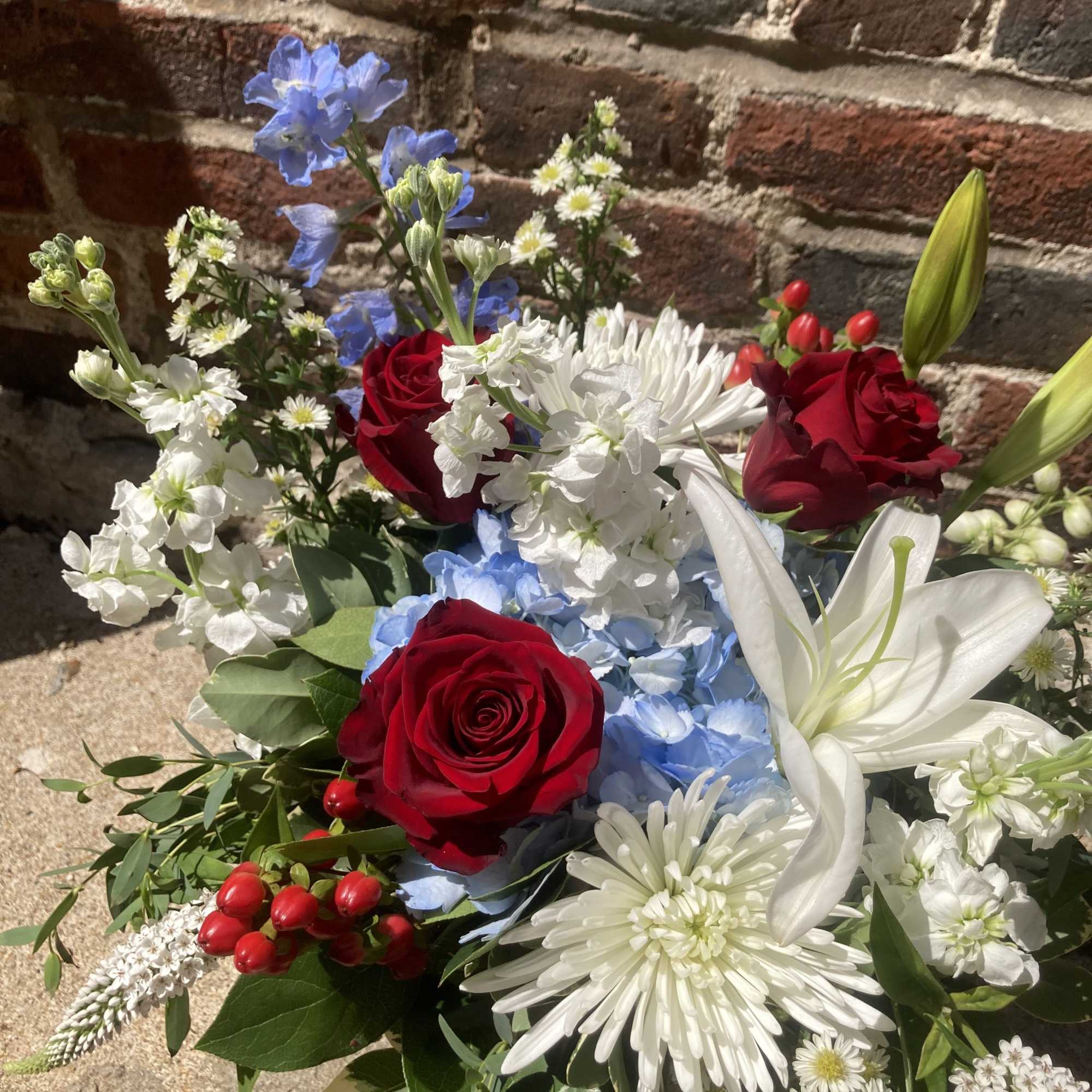 A bold, garden‑style arrangement that greets the eye with patriotic red, white