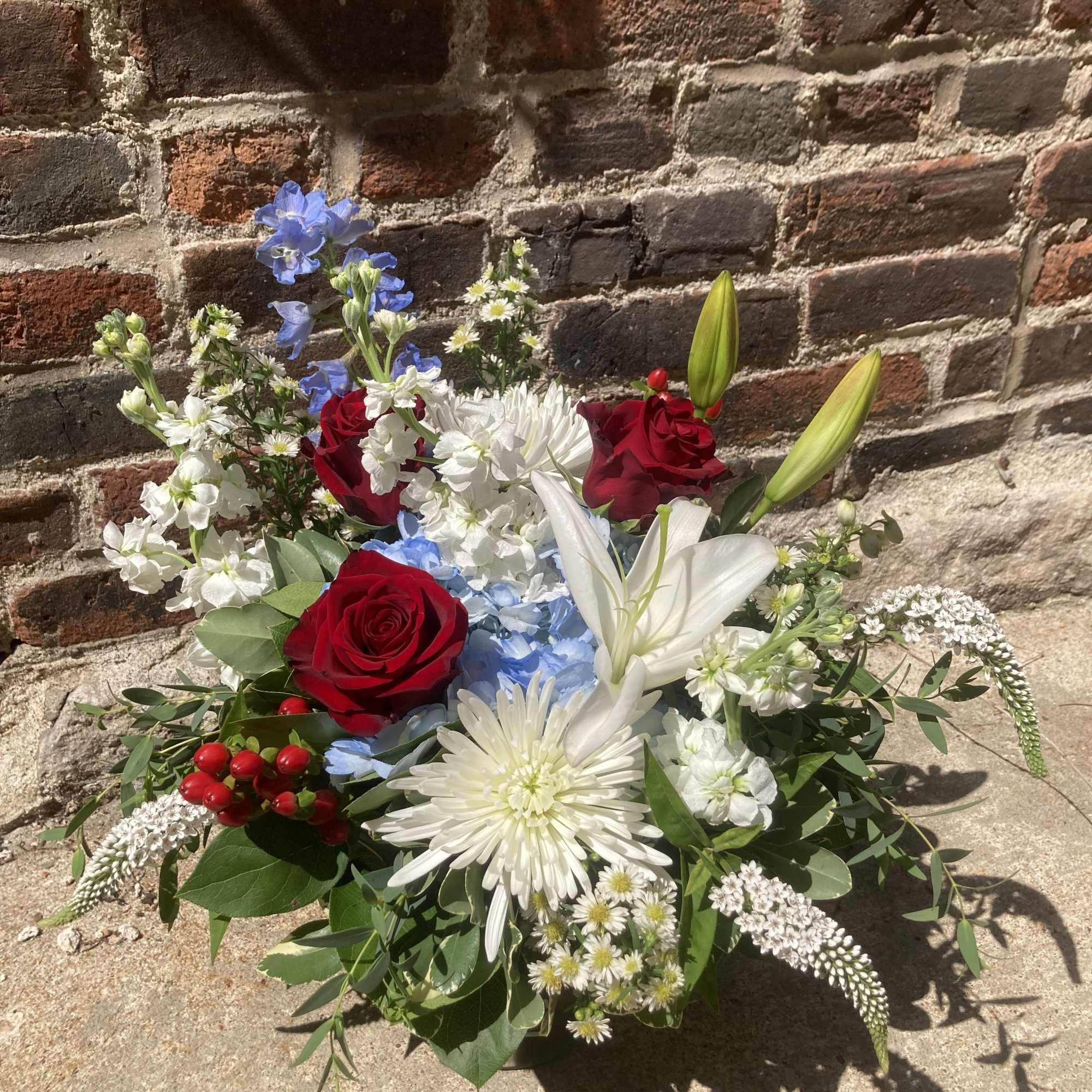 A bold, garden‑style arrangement that greets the eye with patriotic red, white