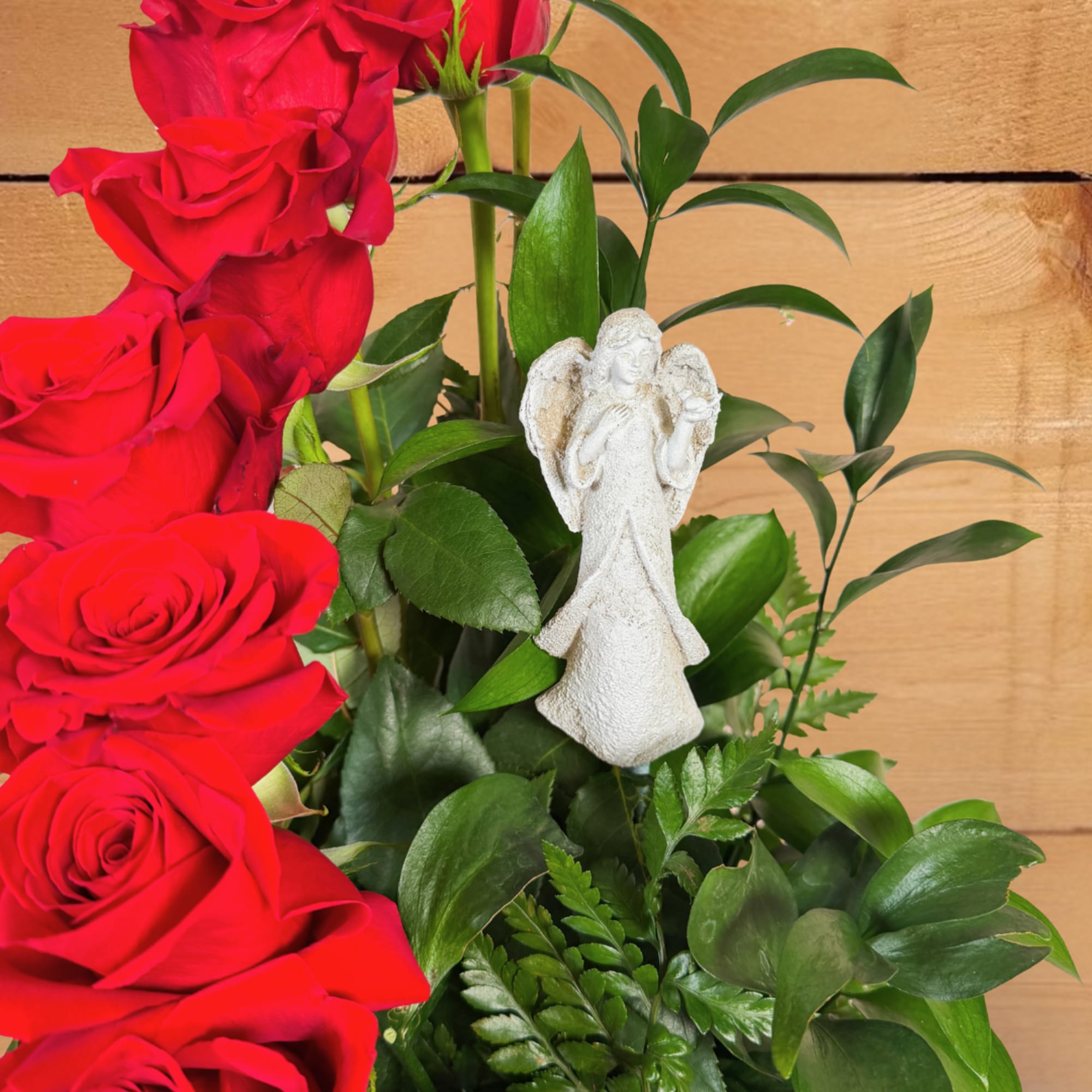 Red roses with greenery and a small angel figurine
