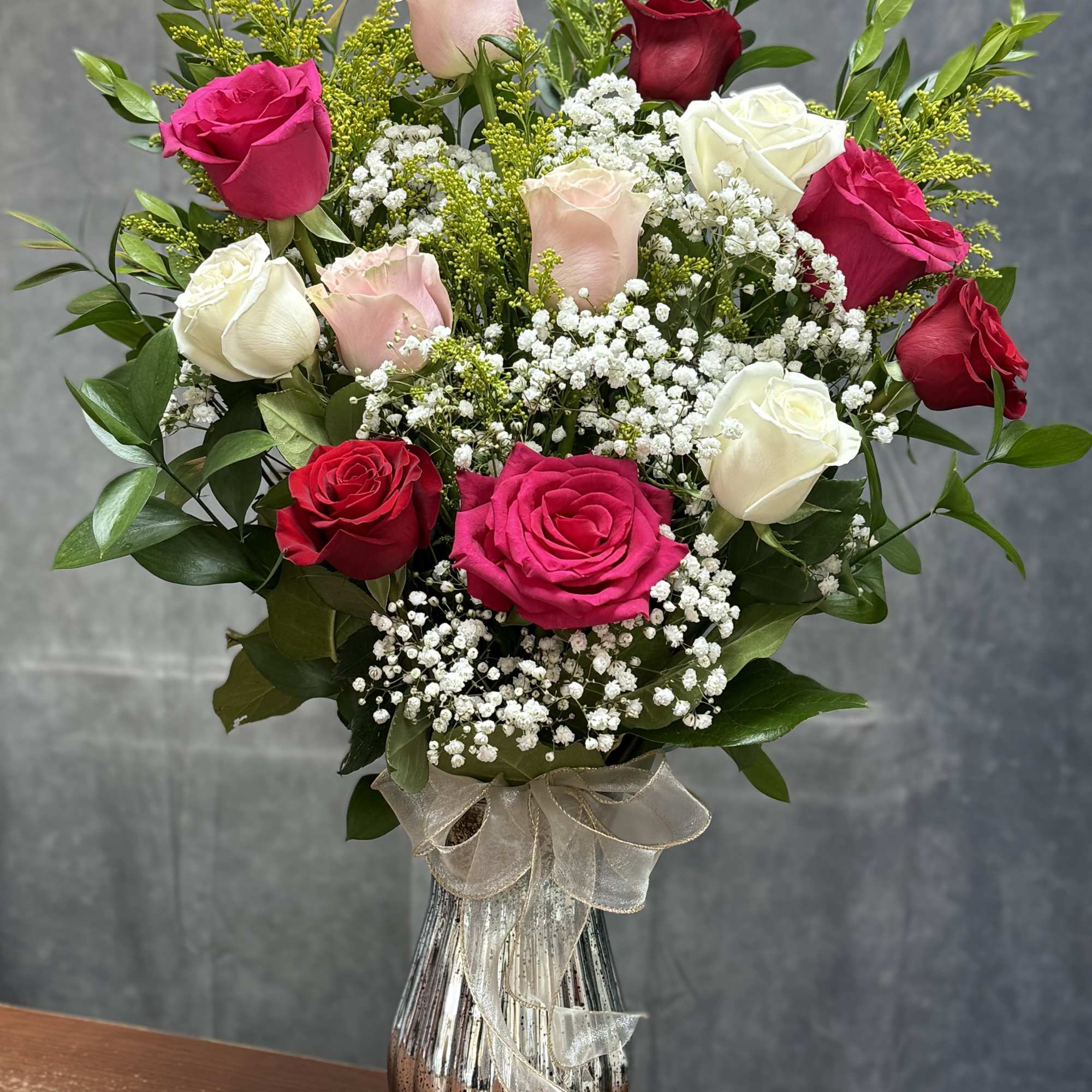 A charming mixed-rose arrangement featuring red, pink, and white roses accented with