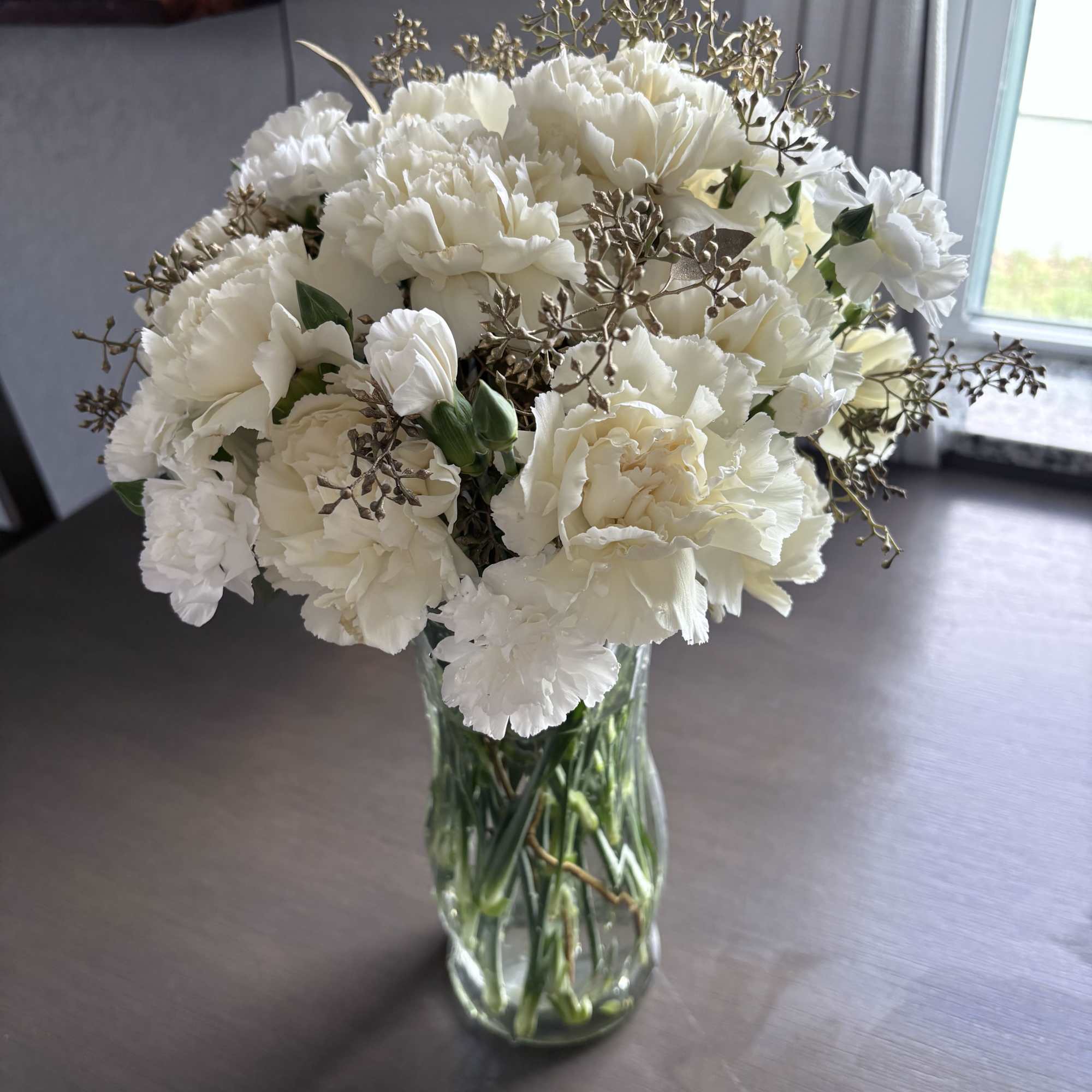 White carnations and roses in a clear glass vase