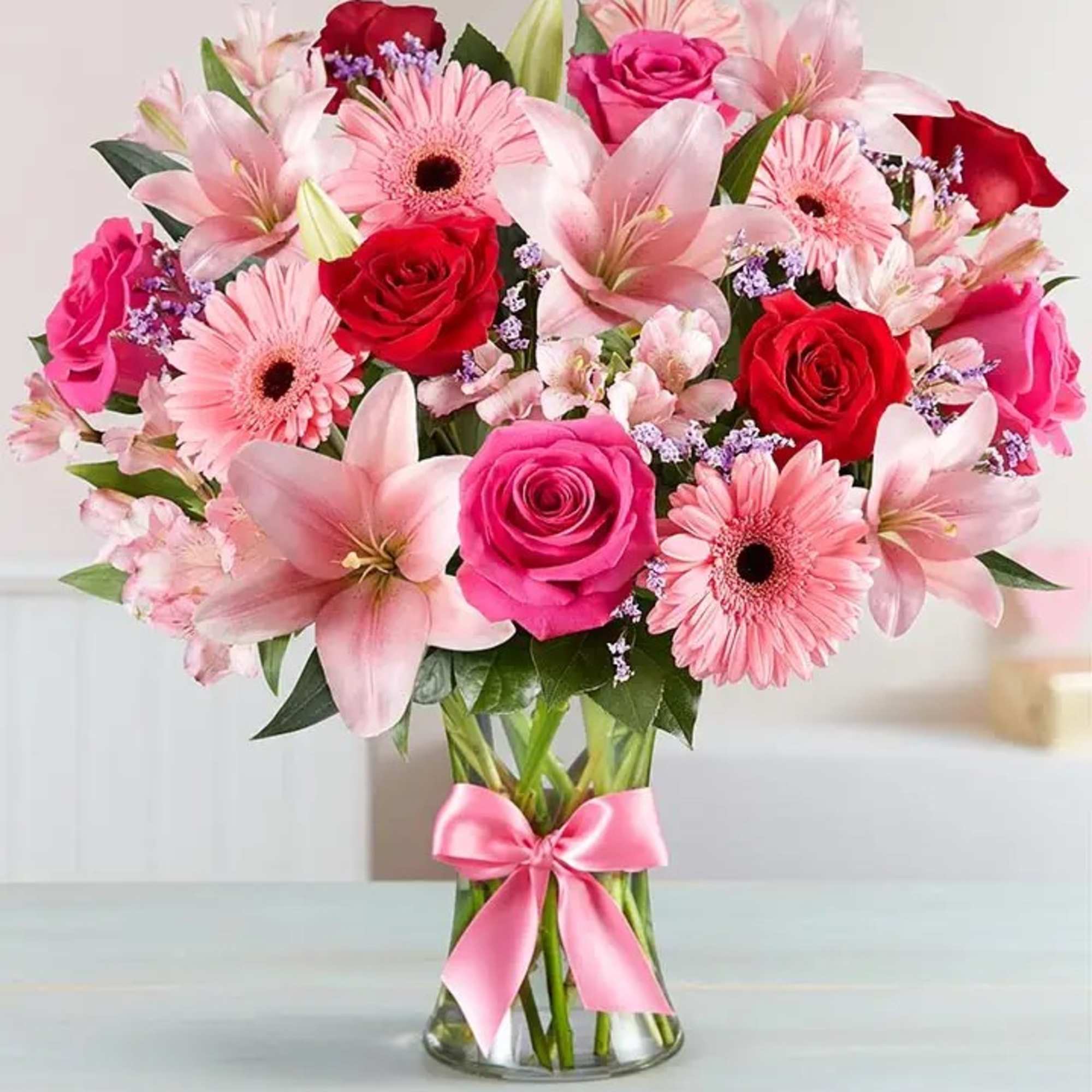 Pink and red mixed bouquet in a glass vase with a pink ribbon