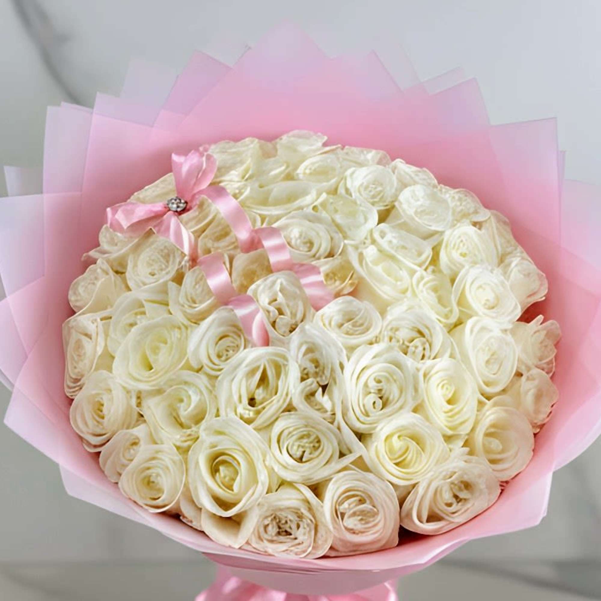 Bouquet of cream roses wrapped in pink paper with a pink ribbon