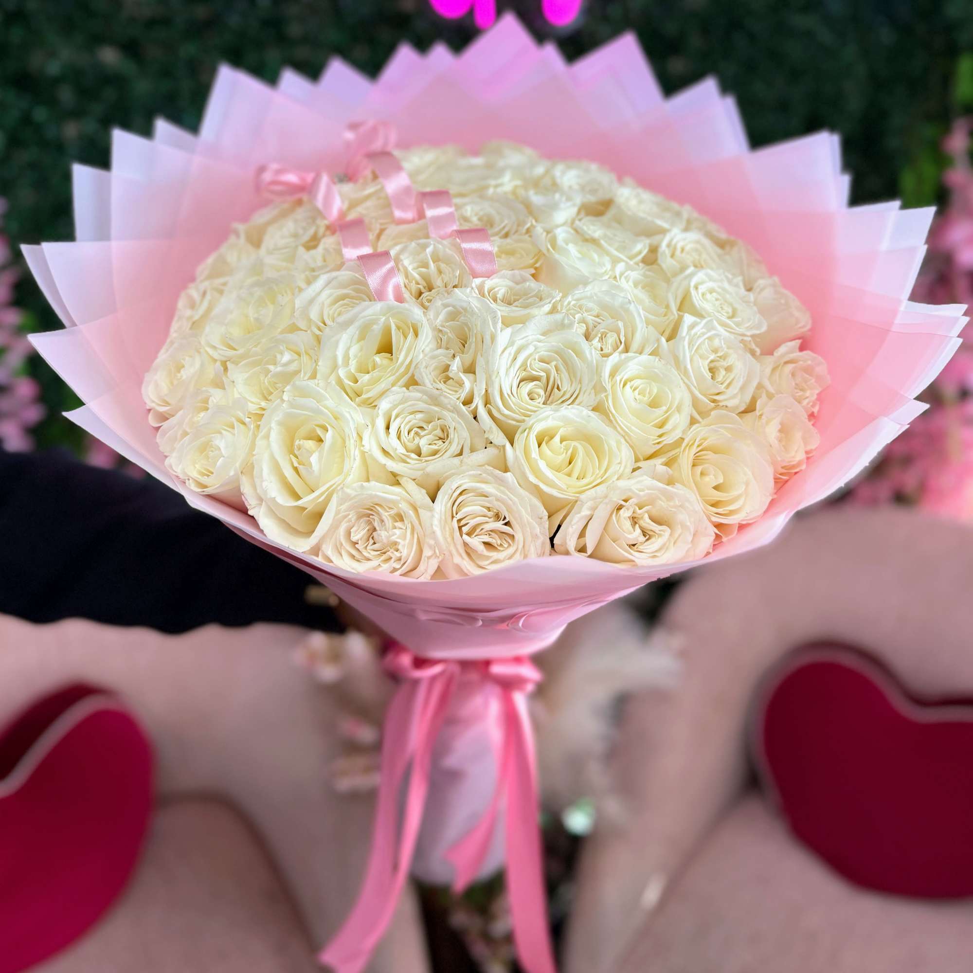 Bouquet of cream roses wrapped in pink paper with ribbon