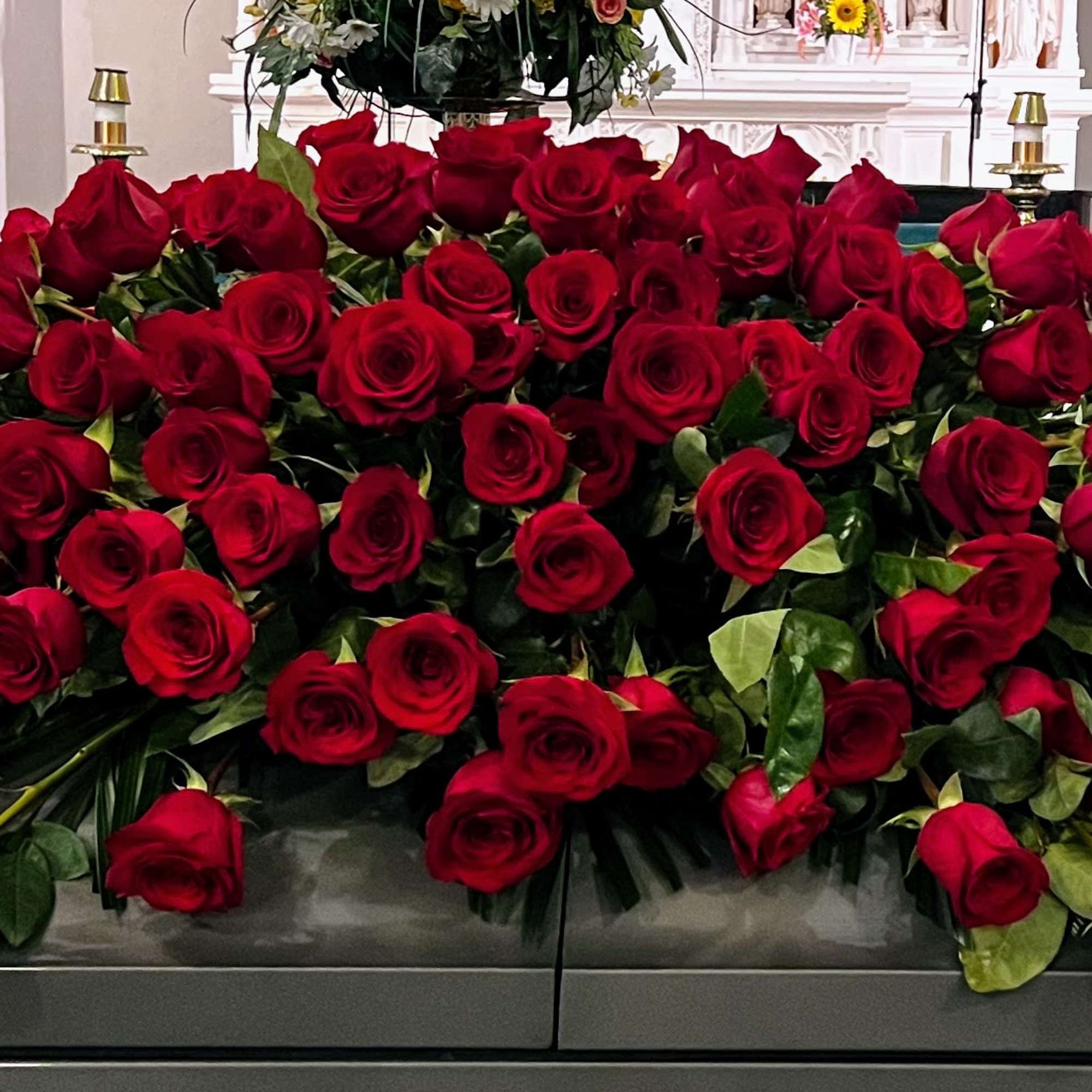 Large casket spray of red roses with greenery
