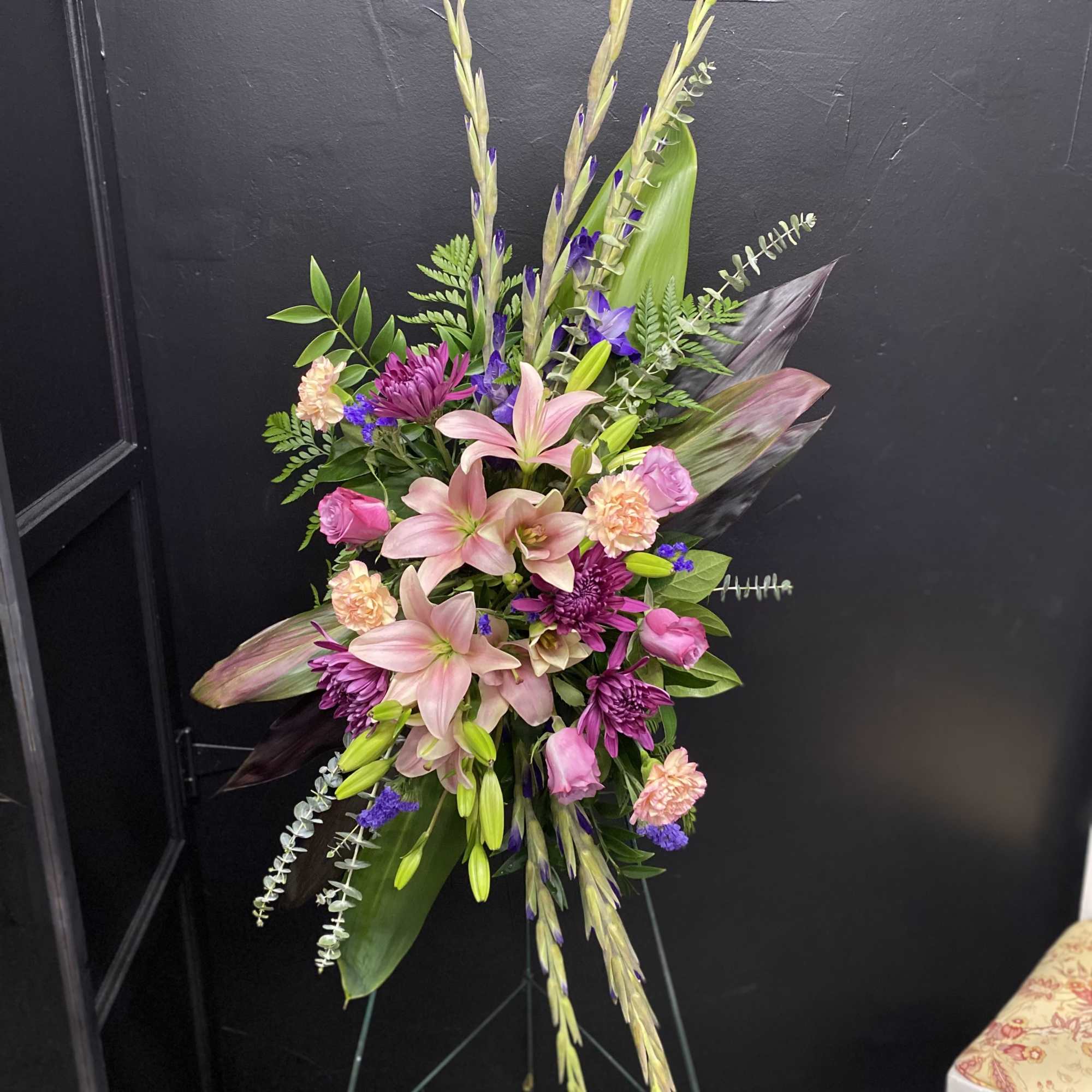 A tall, layered standing spray that reads as both elegant and deeply