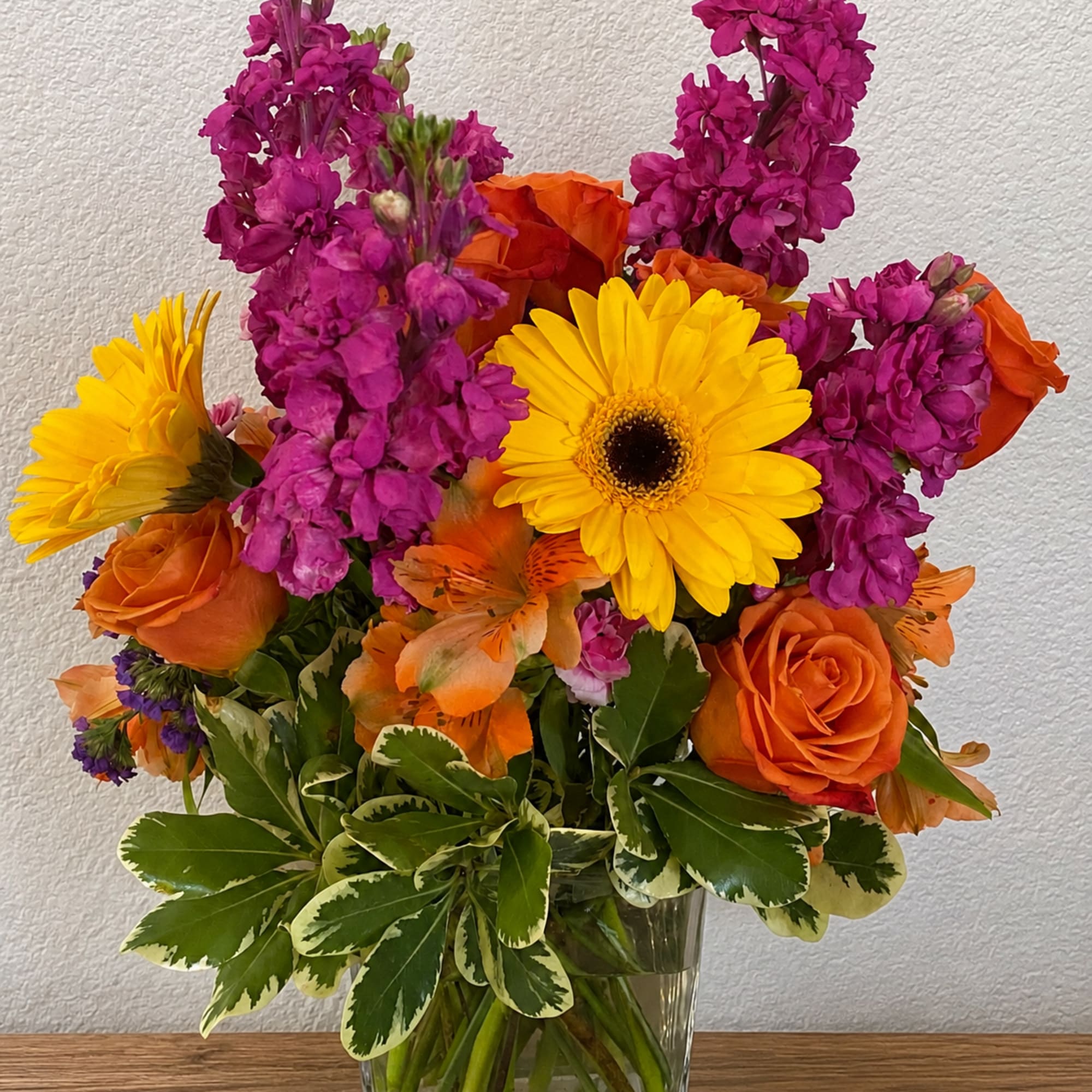 Bright washes of orange roses and yellow gerbera daisies meet tall spikes