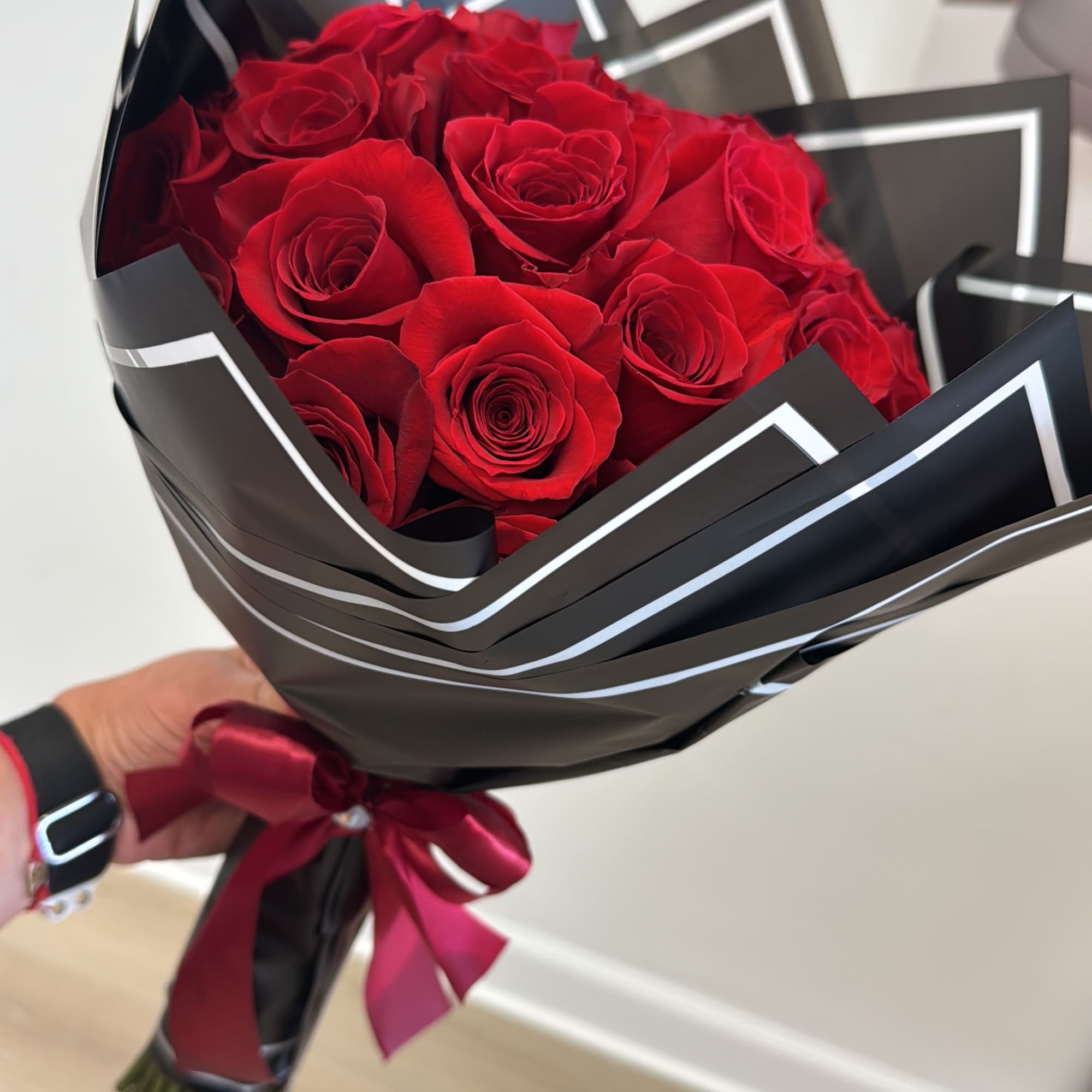 Bouquet of red roses wrapped in black paper with a burgundy ribbon