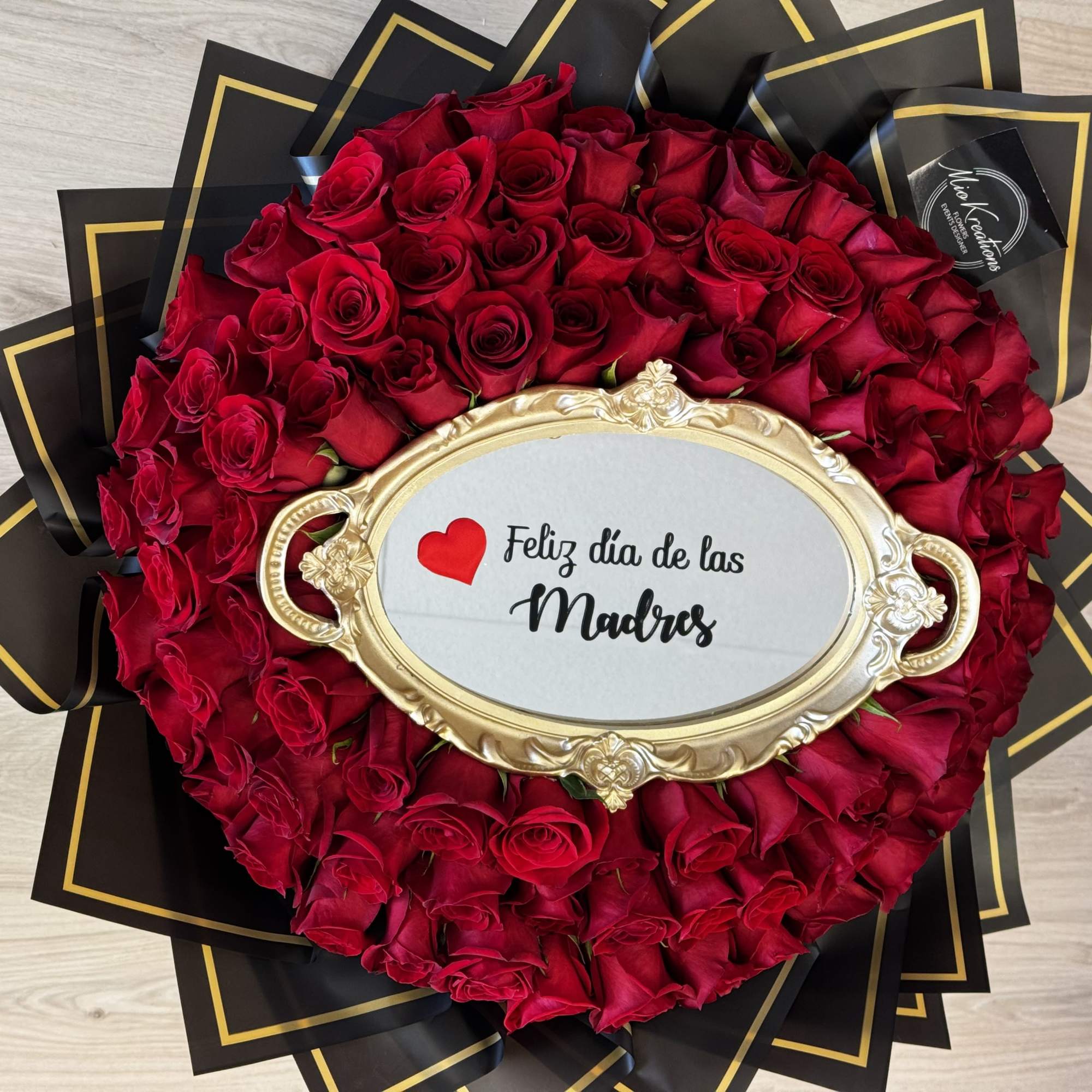 Heart-shaped bouquet of red roses with a gold frame reading Feliz día de las Madres