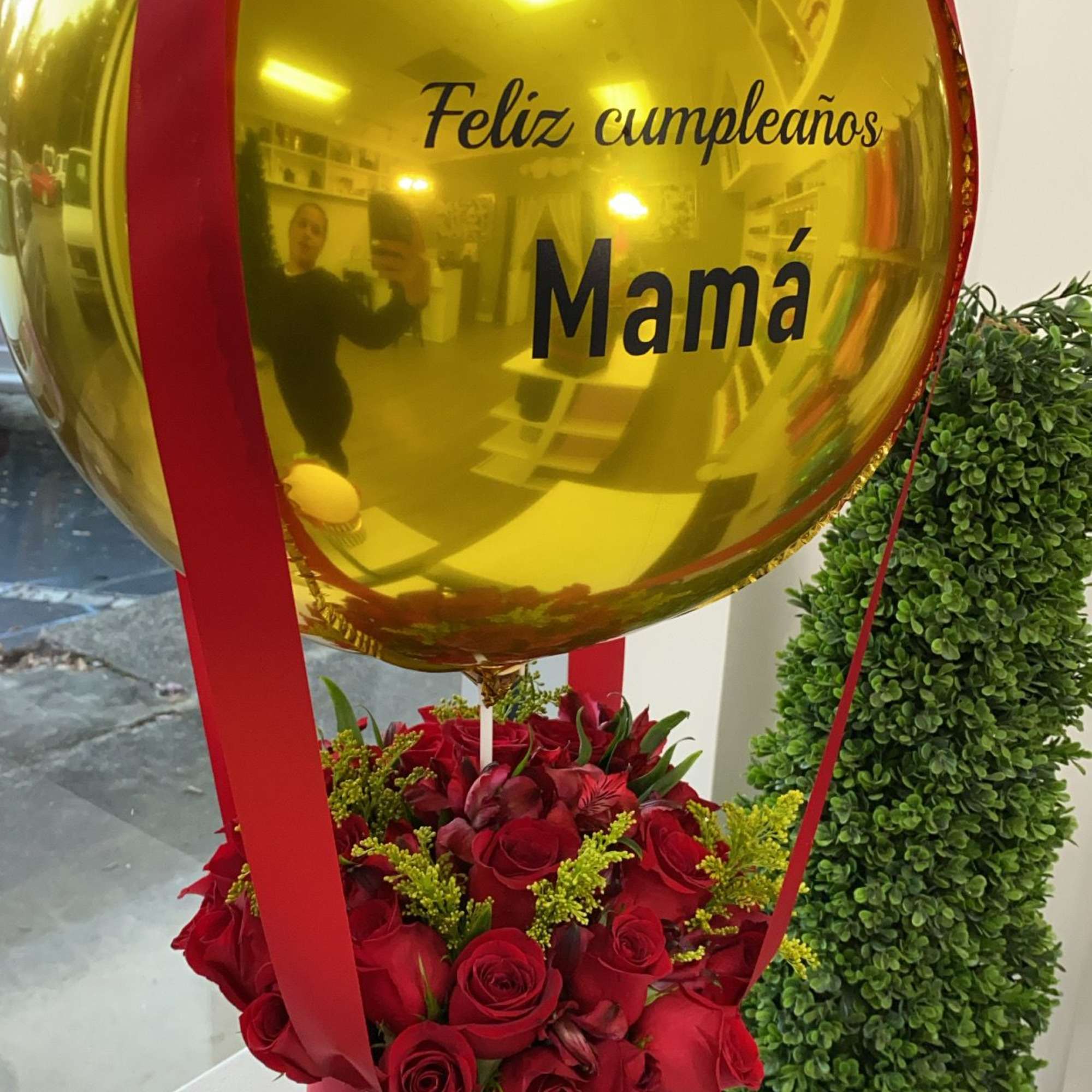 Gold birthday balloon above red roses and chocolates in a gift box