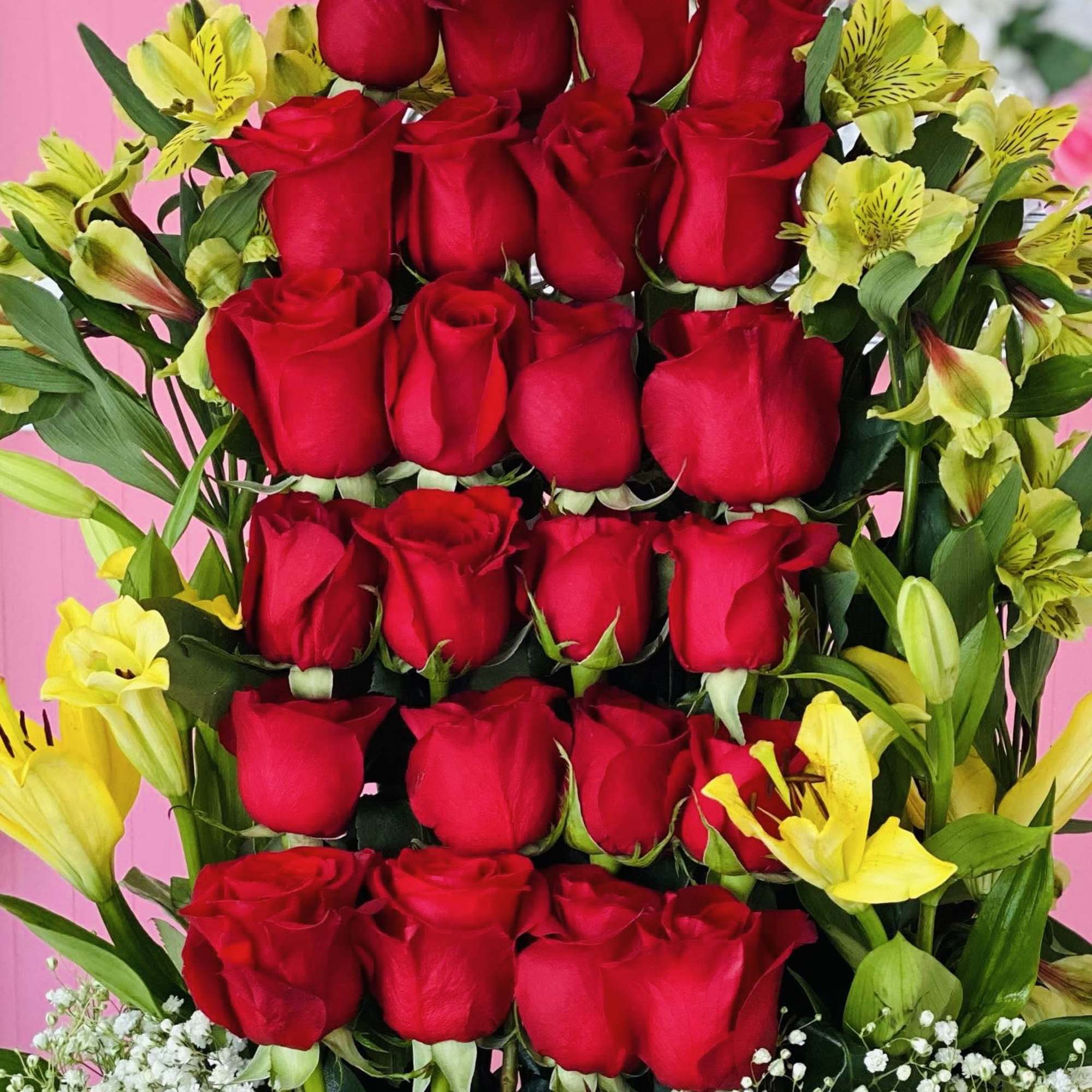 Tall arrangement of red roses with yellow alstroemeria and baby's breath