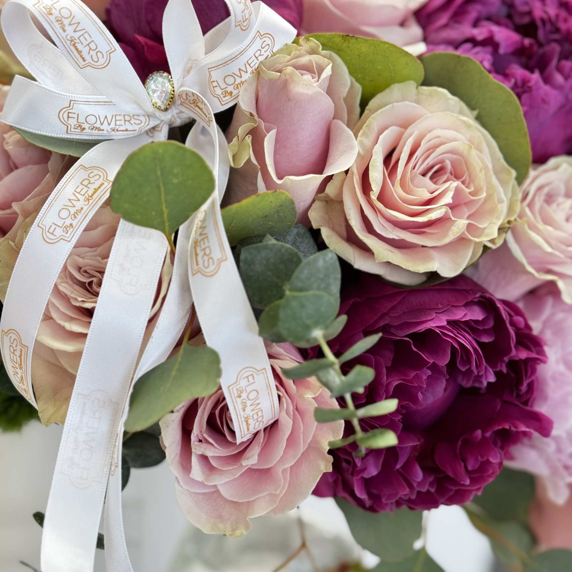Pink and magenta roses with eucalyptus and a white ribbon bow