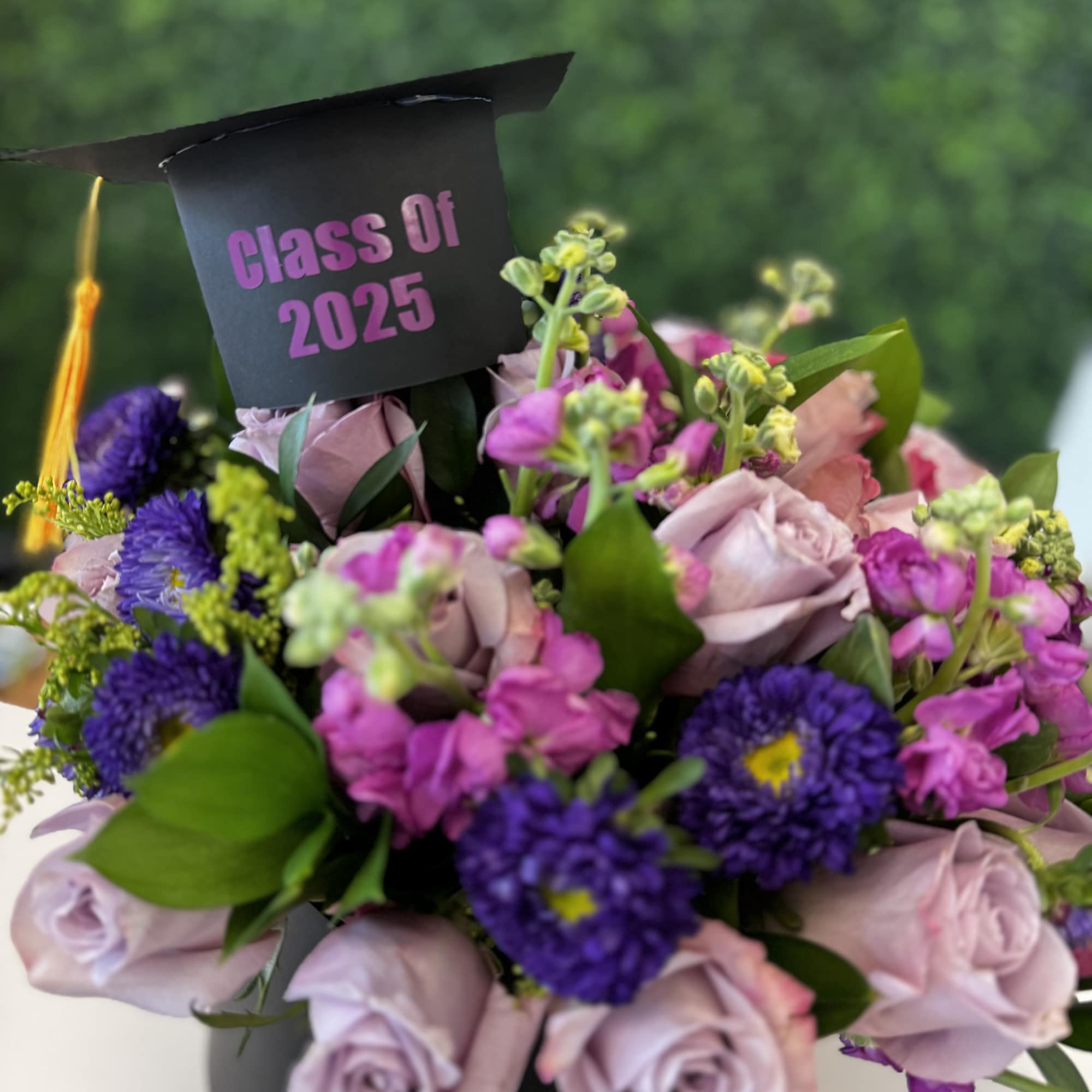 Bouquet of pink and purple flowers with a graduation cap topper