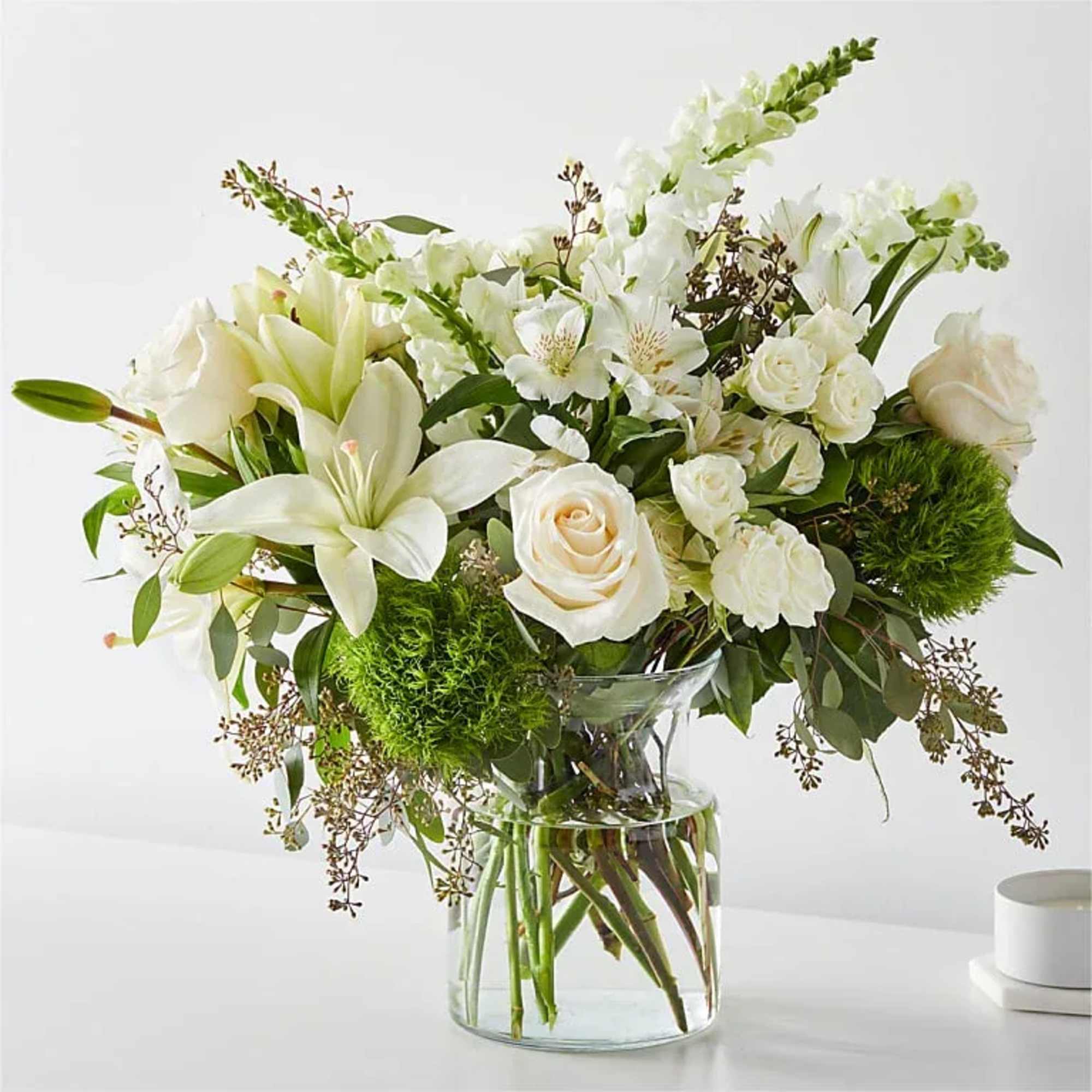 White lilies and roses arranged in a clear glass vase