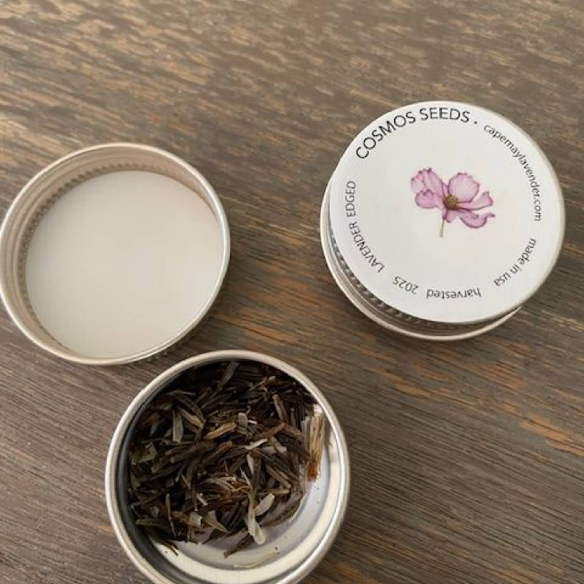 Open tin of dried cosmos seeds on a wooden surface