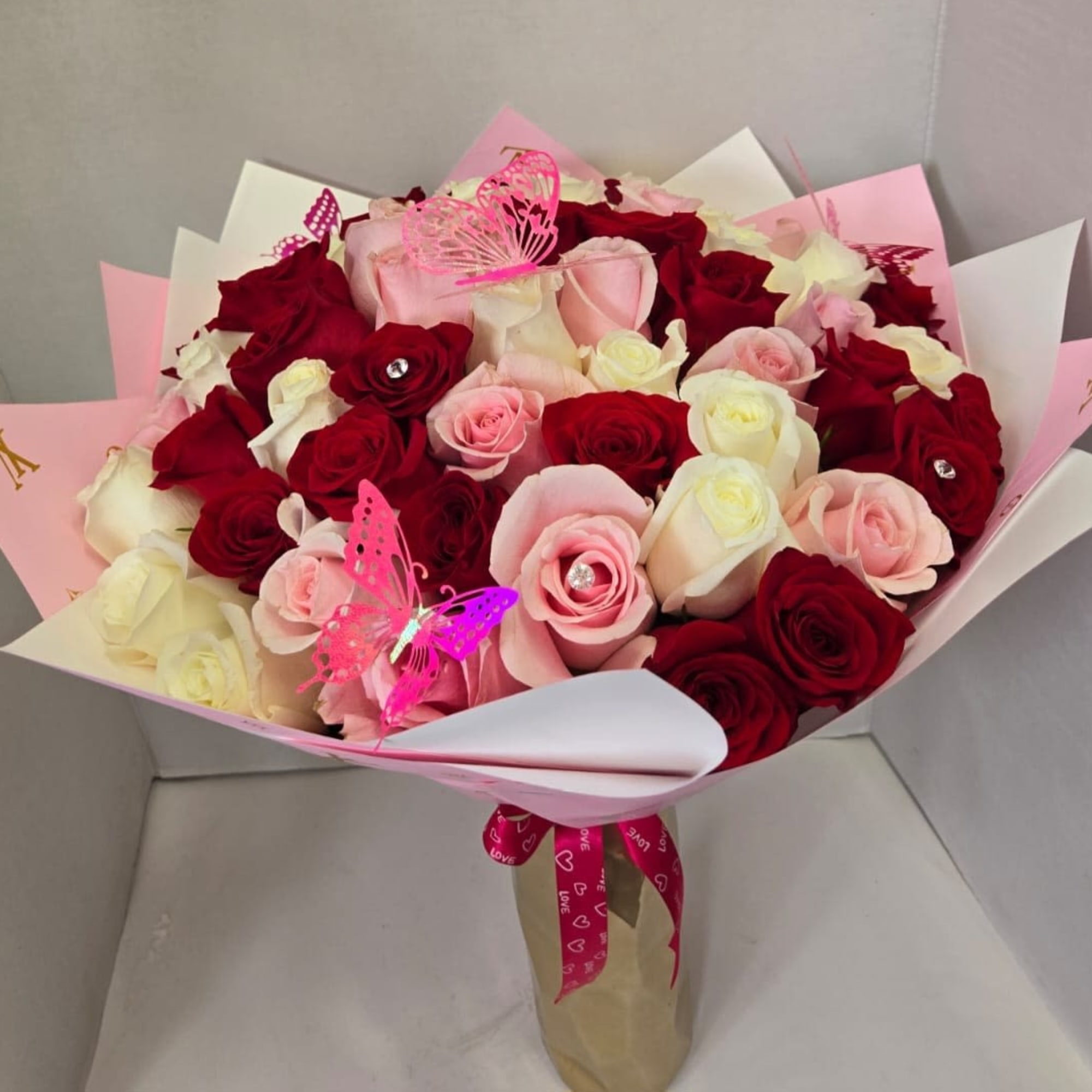Bouquet of red, pink, and white roses with butterfly picks