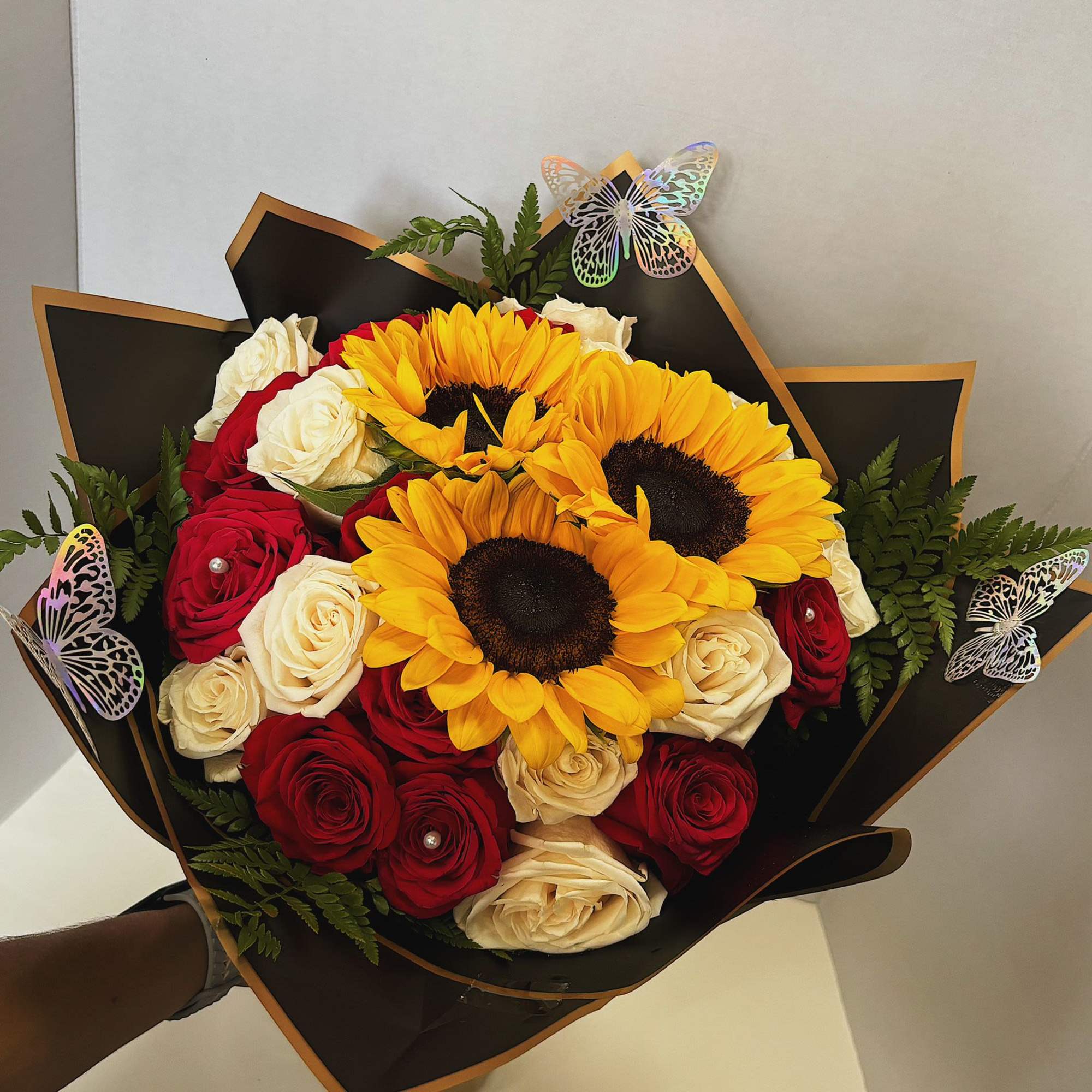 Bouquet of red and white roses with yellow sunflowers in black wrap