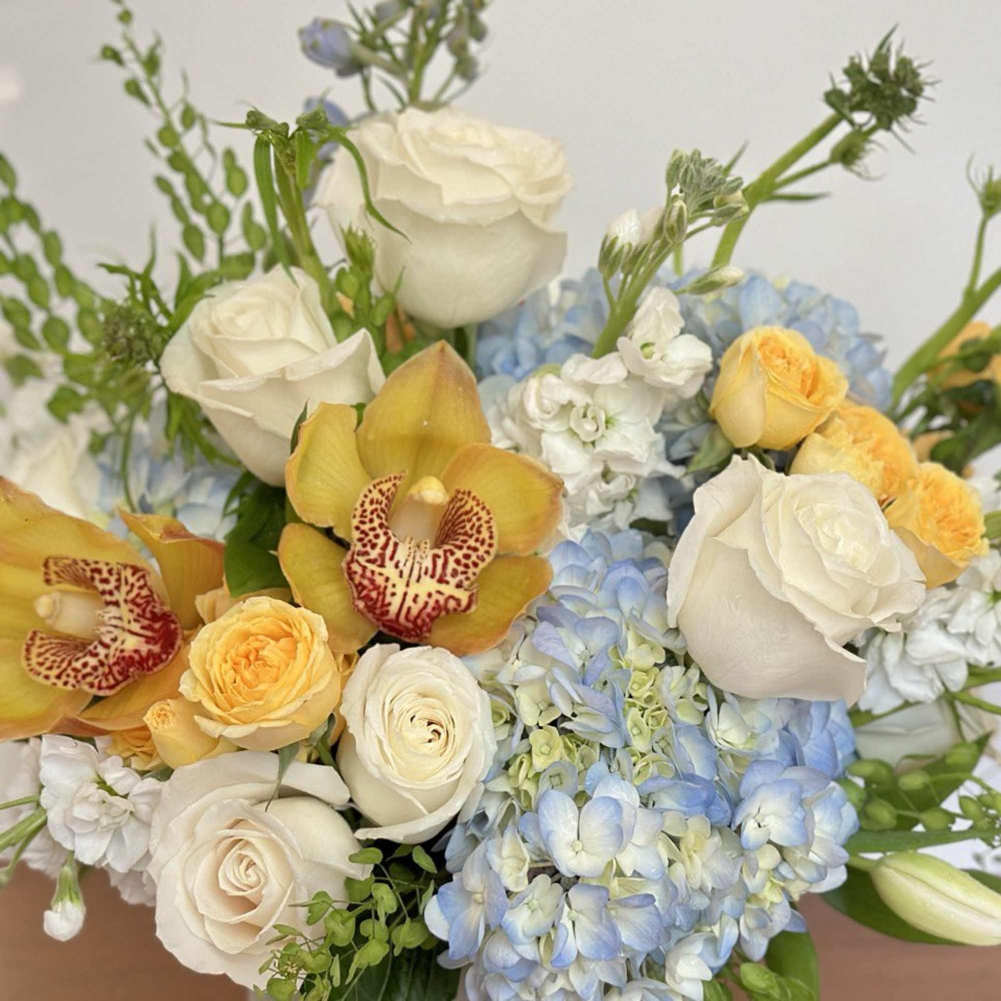 Bouquet of white roses, blue hydrangeas, and yellow orchids