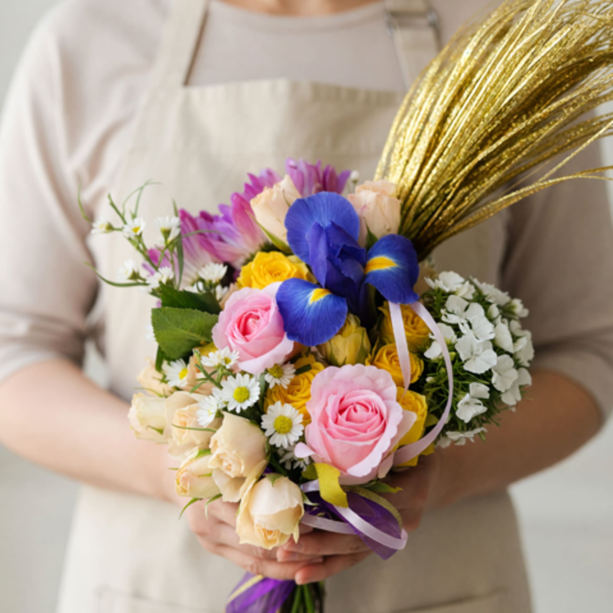 Soft pink and pale yellow roses mingle with vivid blue irises and