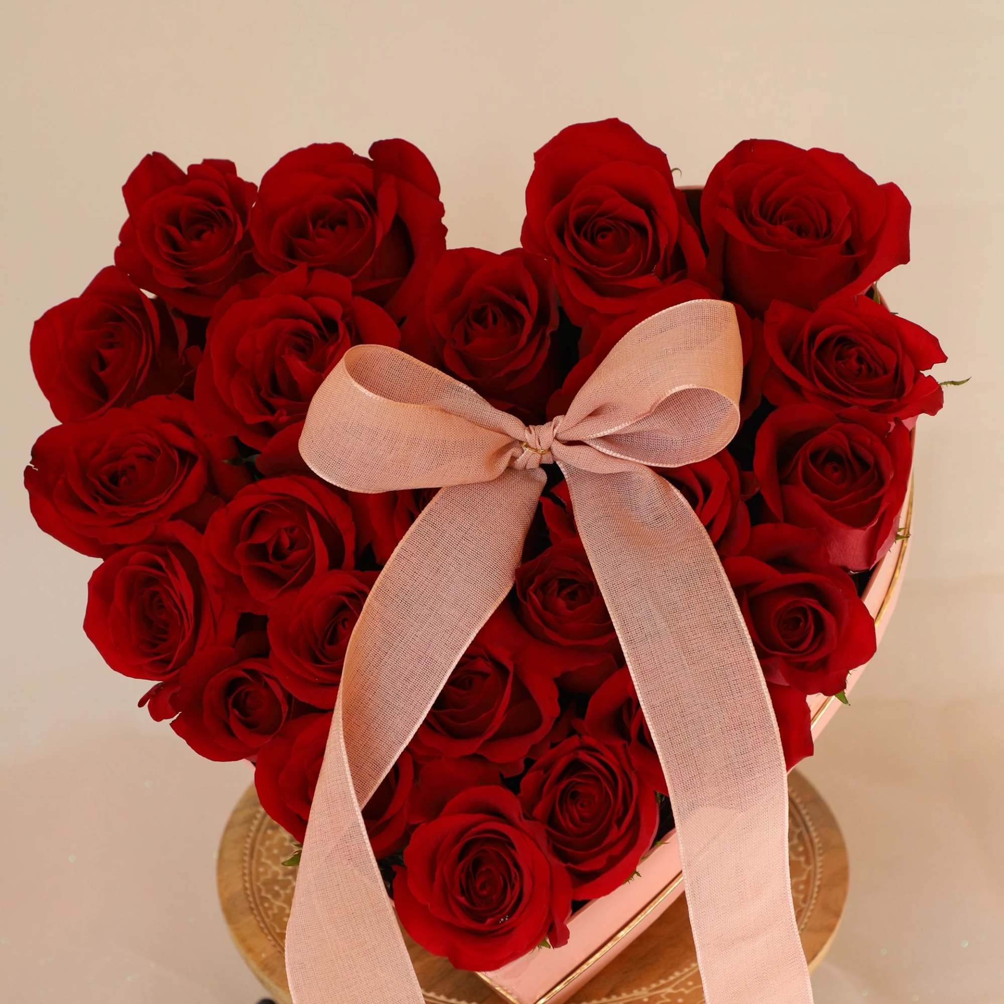 Heart-shaped bouquet of red roses with a pink ribbon bow
