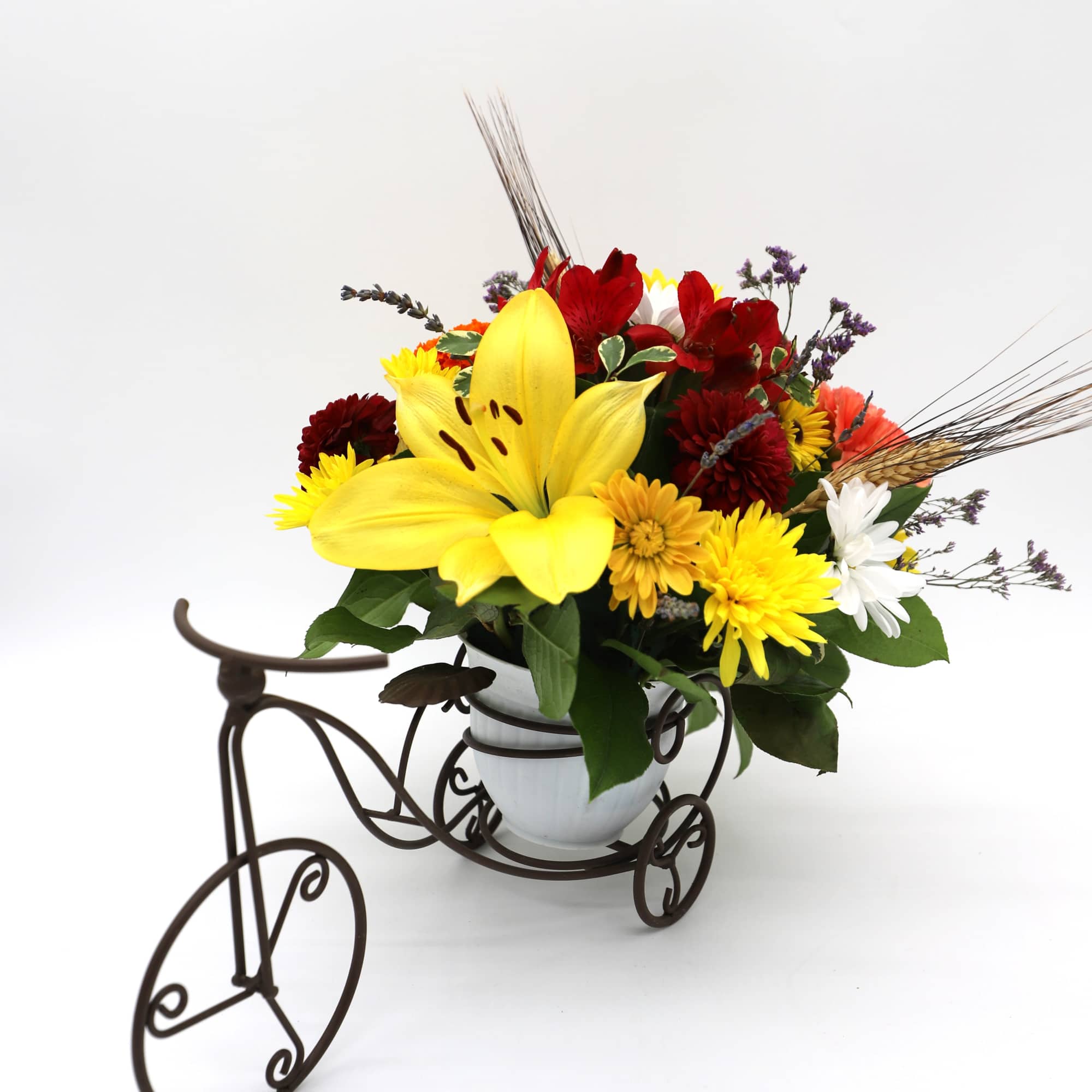 Mixed bouquet with a large yellow lily in a white vase on a decorative tricycle stand
