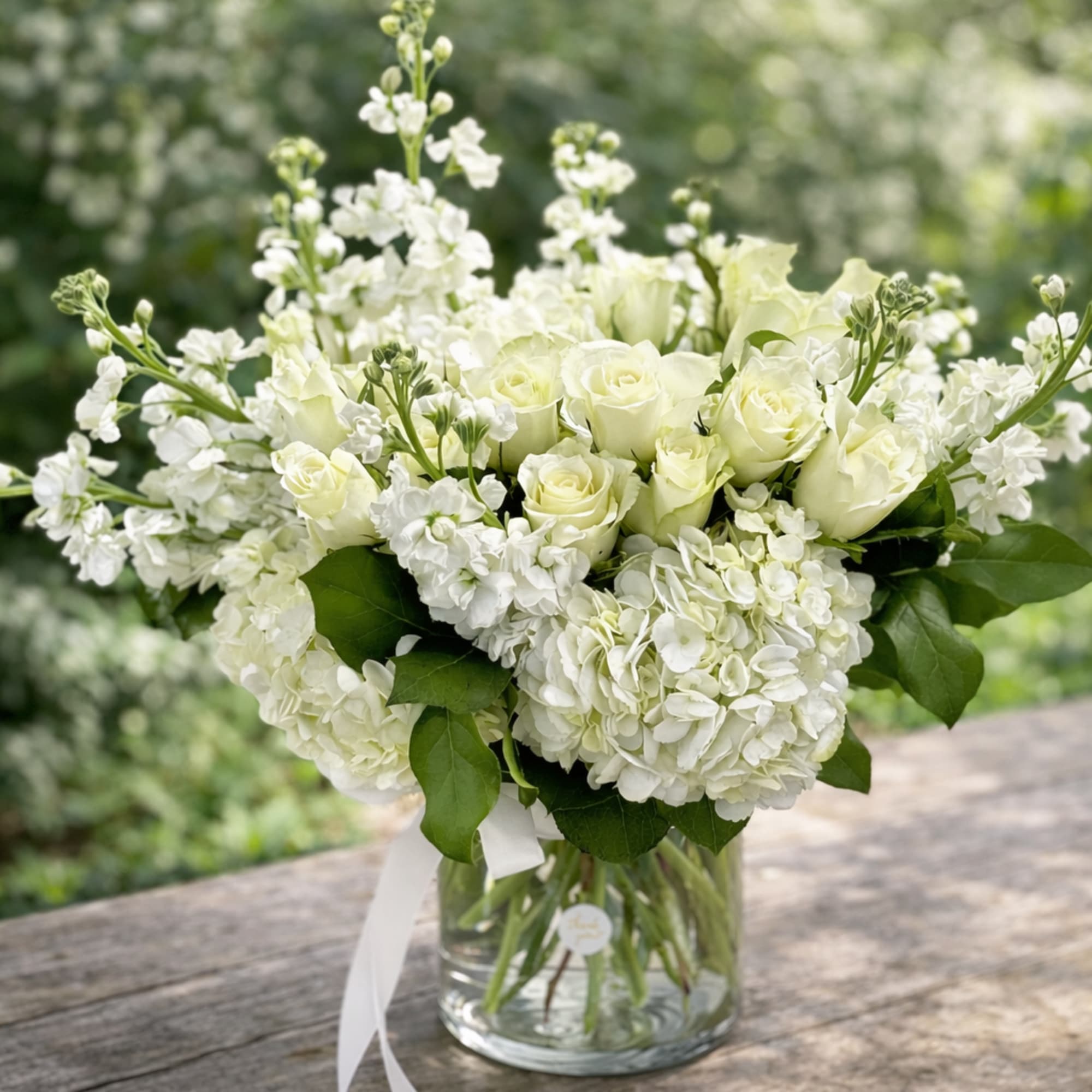 Creamy white roses and full white hydrangeas form a serene, rounded bouquet