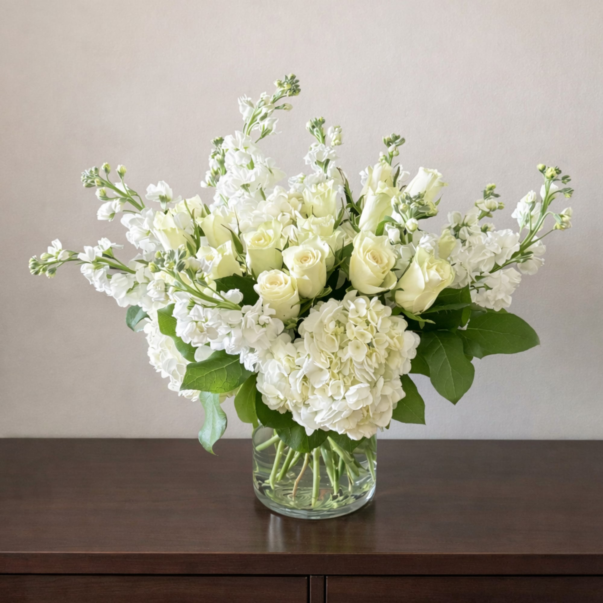 Creamy white roses and full white hydrangeas form a serene, rounded bouquet