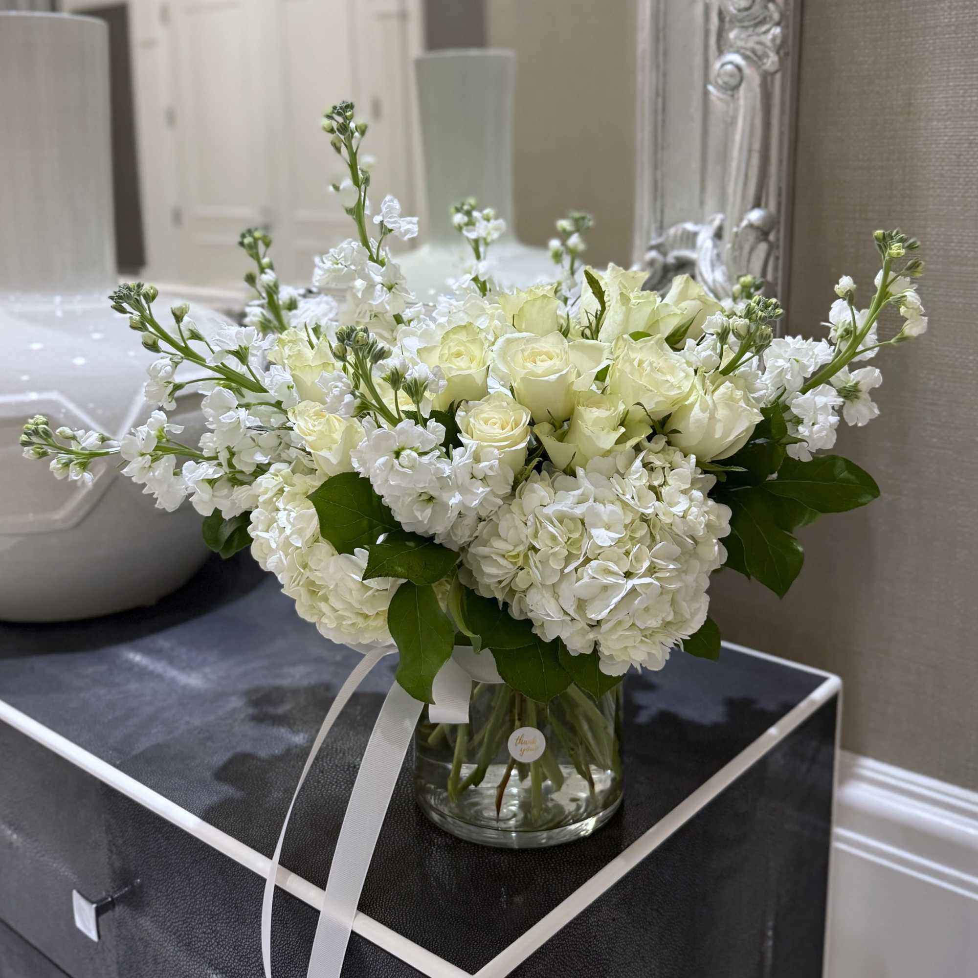 Creamy white roses and full white hydrangeas form a serene, rounded bouquet