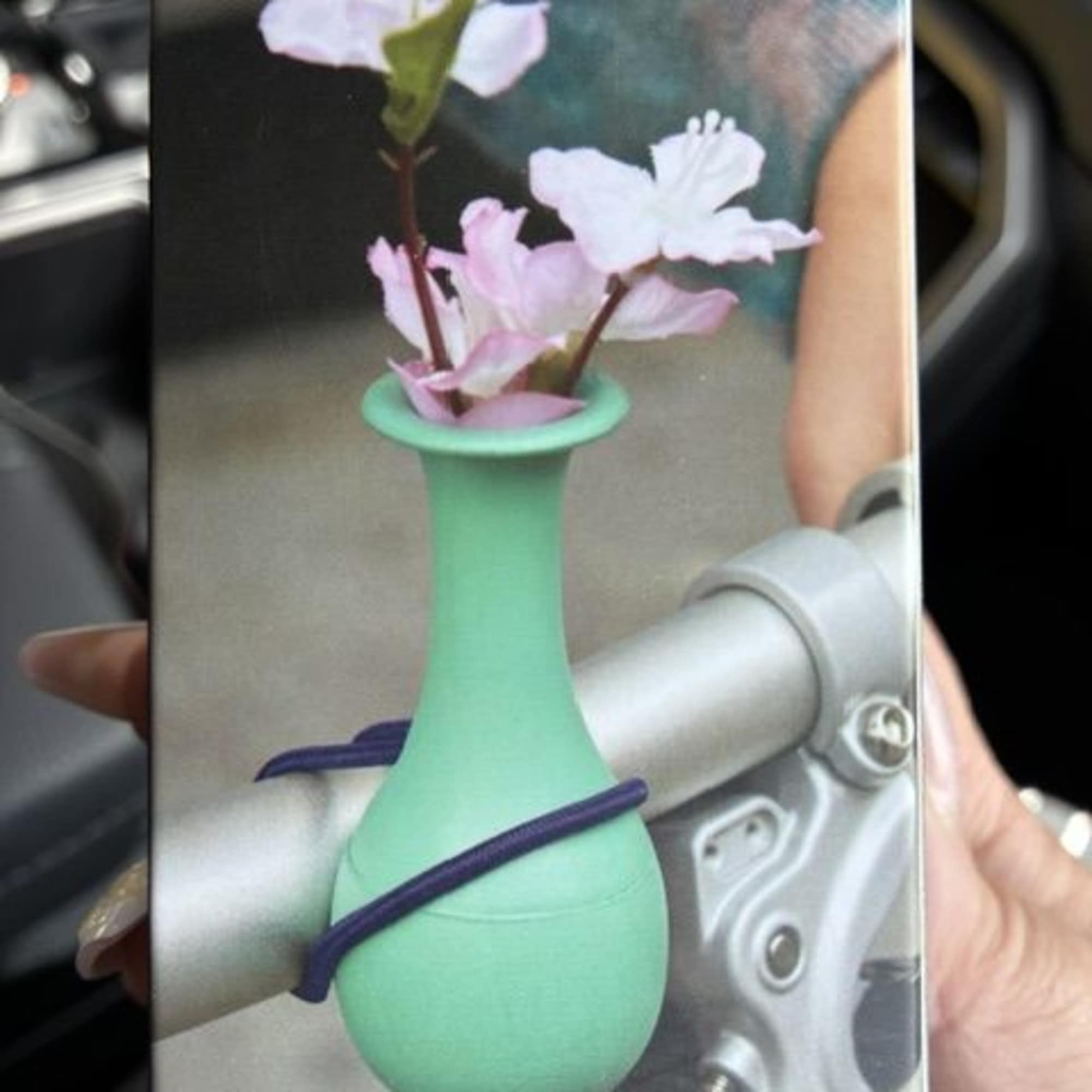 A mint-green bike vase clipped to a handlebar makes a cheerful, unexpected