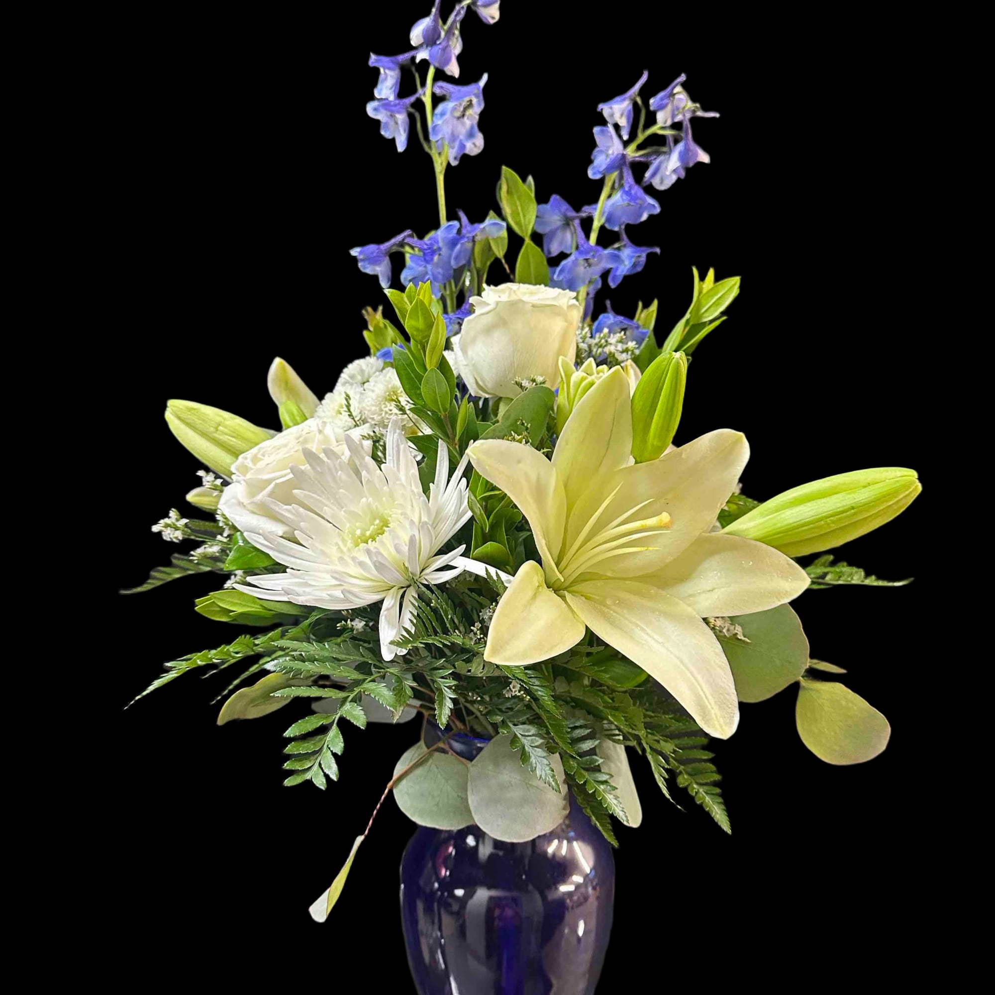 White lilies, blue delphinium, and chrysanthemums in a blue vase