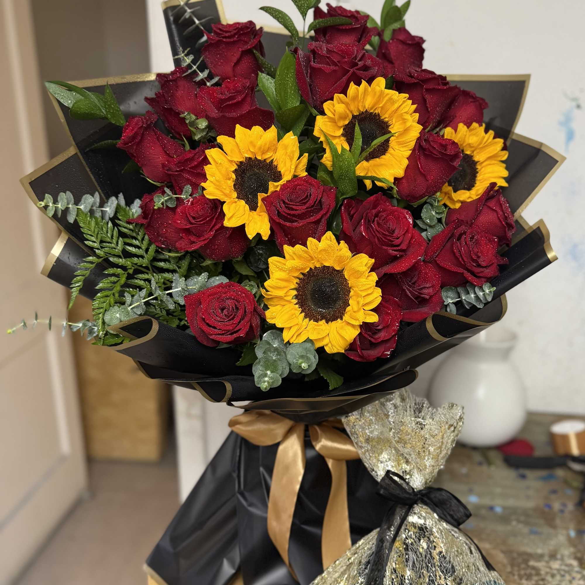 Deep red roses paired with sunny yellow sunflowers create a bold, dramatic