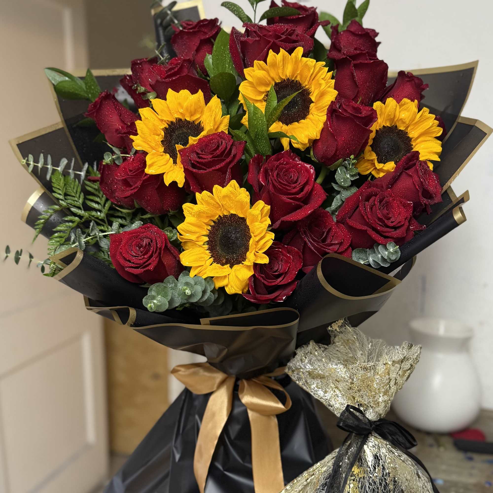 Deep red roses paired with sunny yellow sunflowers create a bold, dramatic