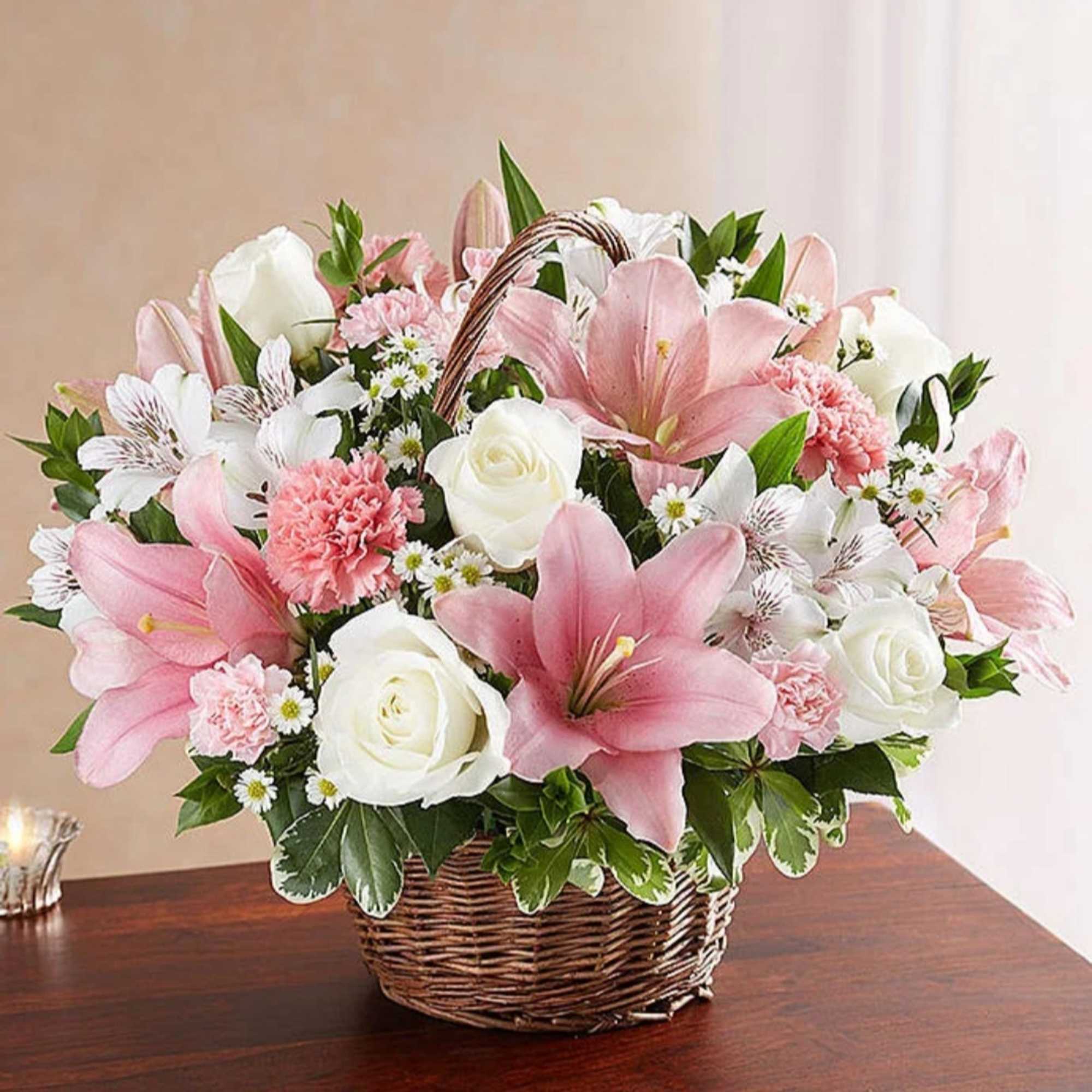 Pink lilies and white roses arranged in a wicker basket
