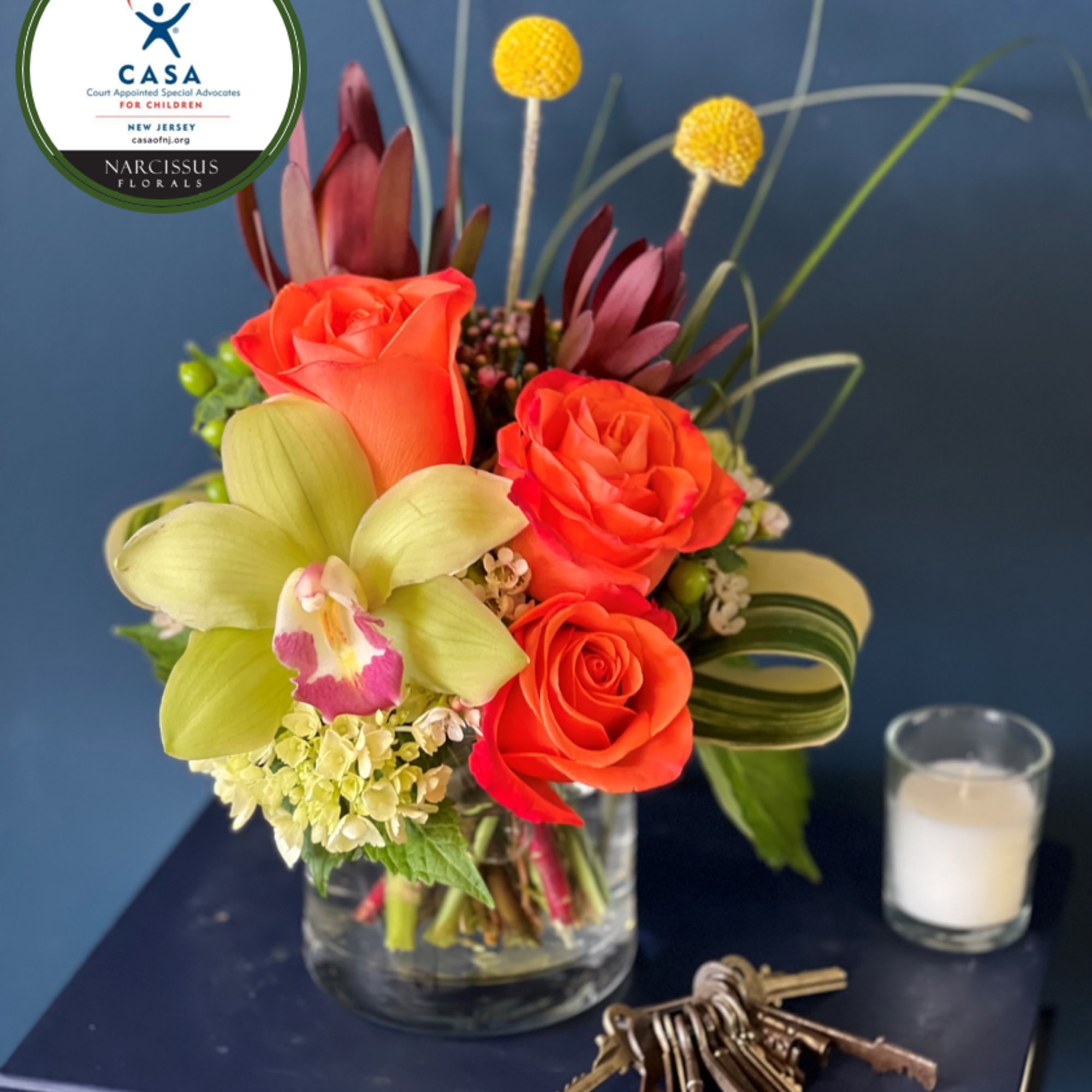 Orange roses and a pale green orchid in a glass vase