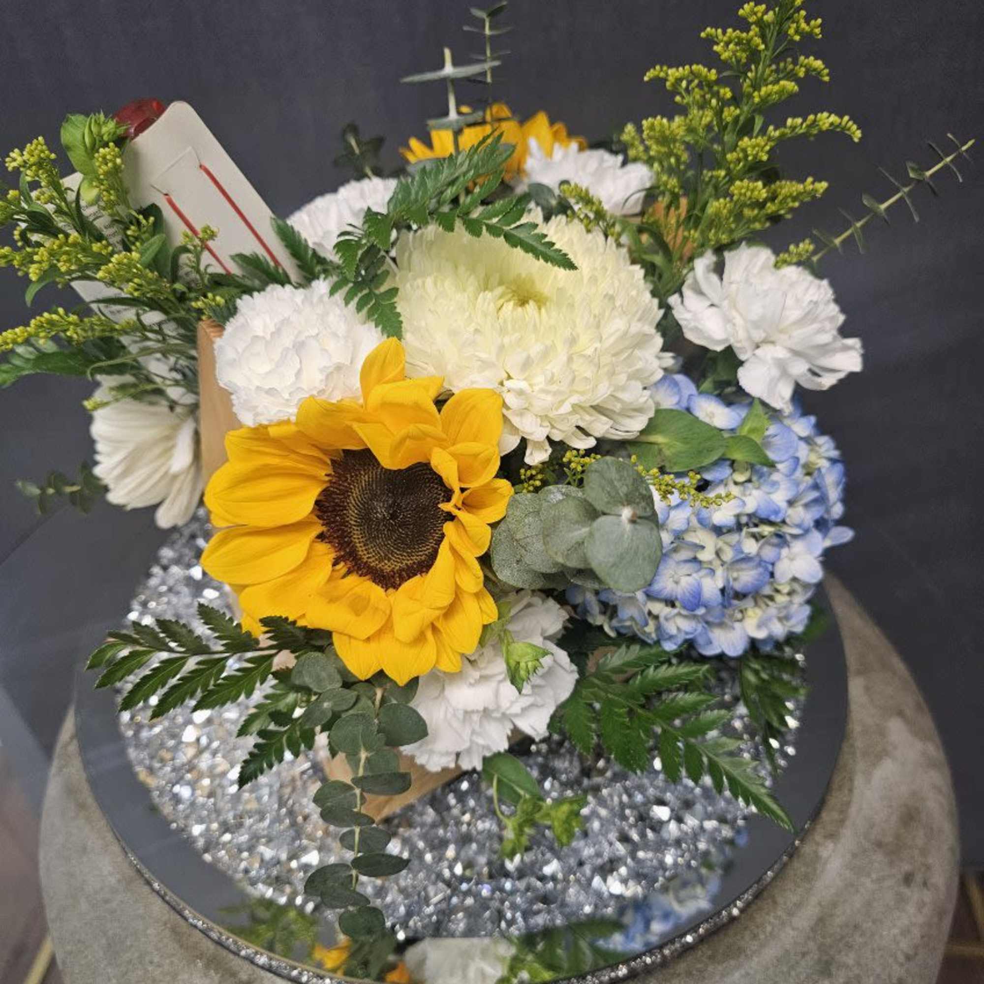 A bold golden sunflower takes center stage in this cheerful flower arrangement