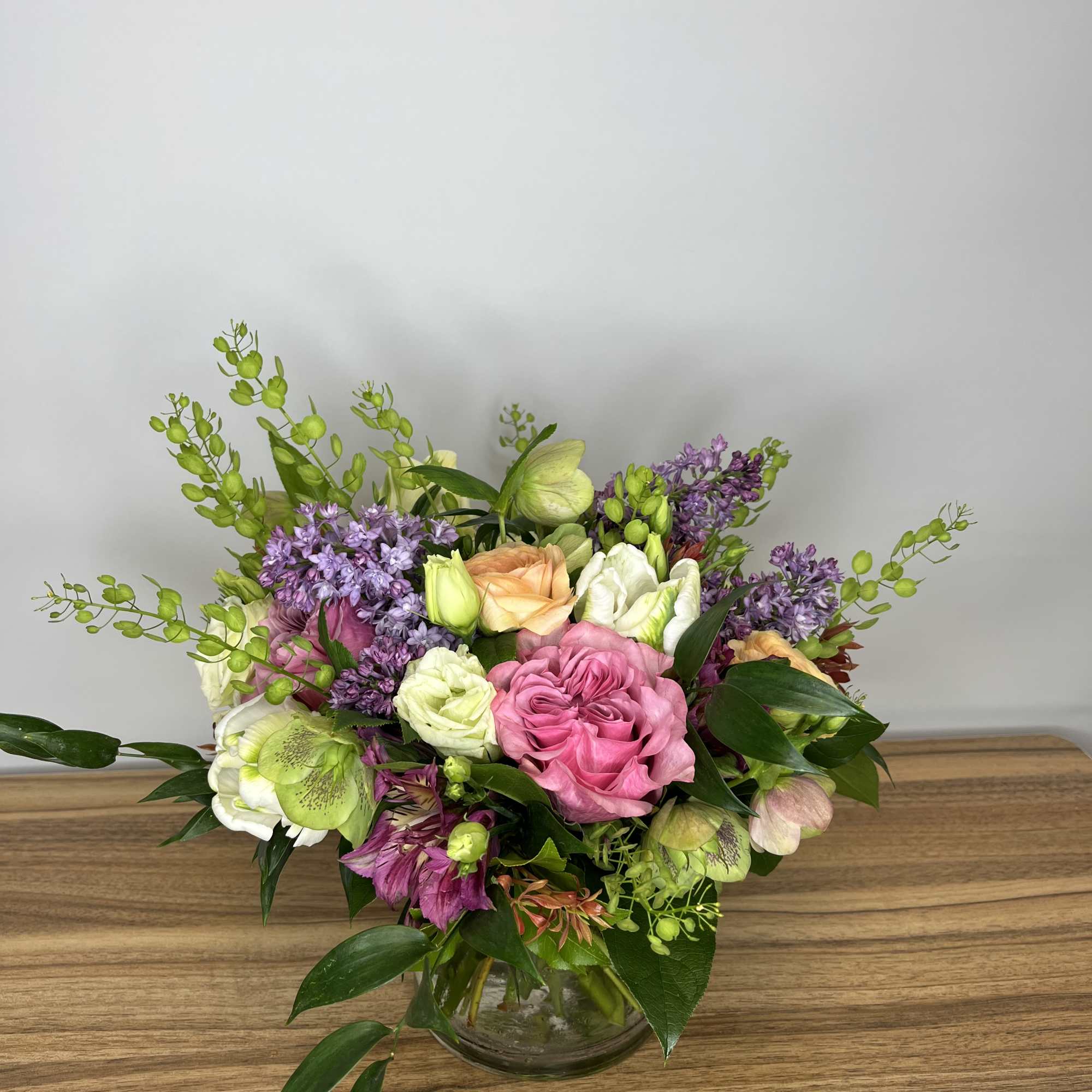 Mixed bouquet of pink, peach, white, and purple flowers in a glass vase