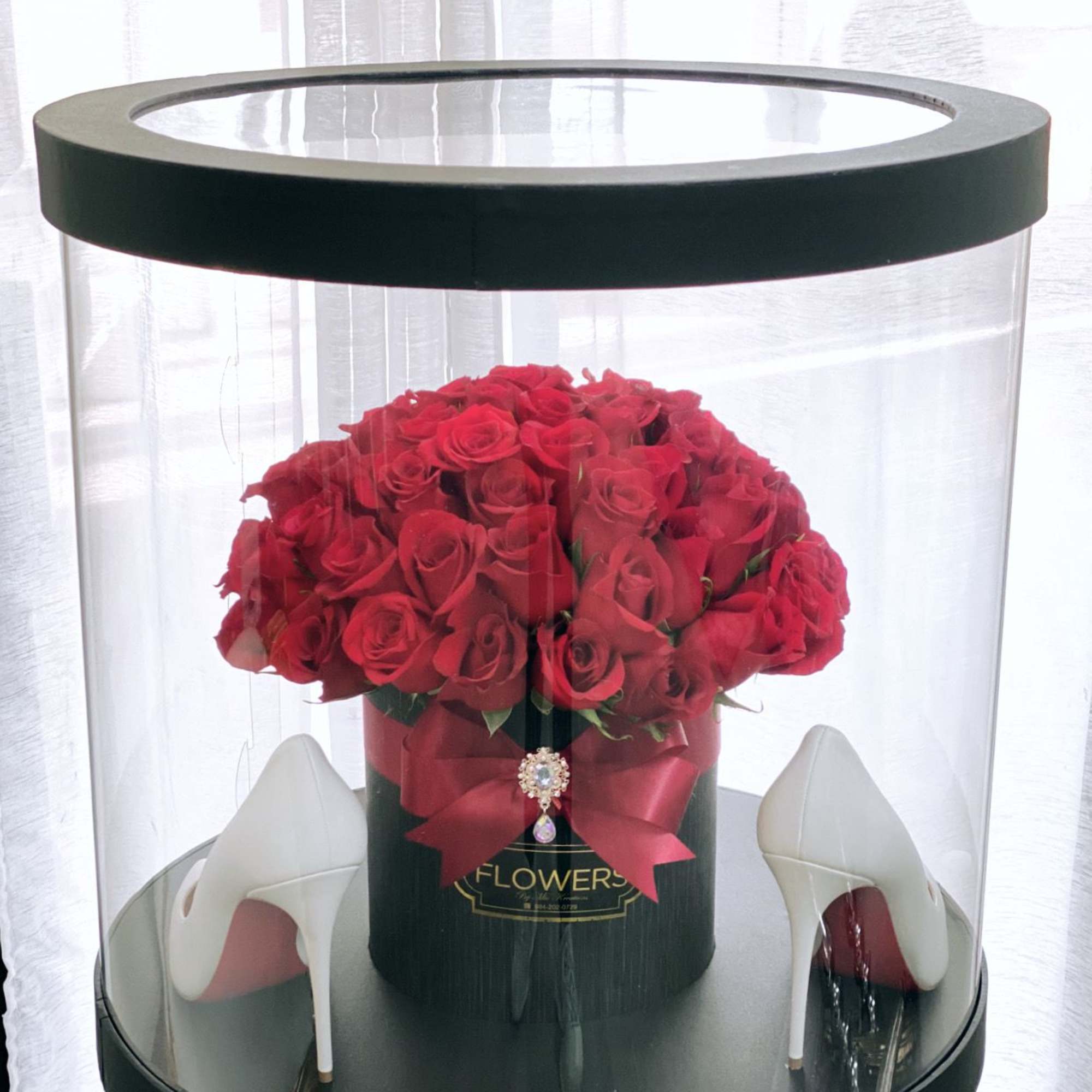 Red roses in a black hatbox with white high heels beside it