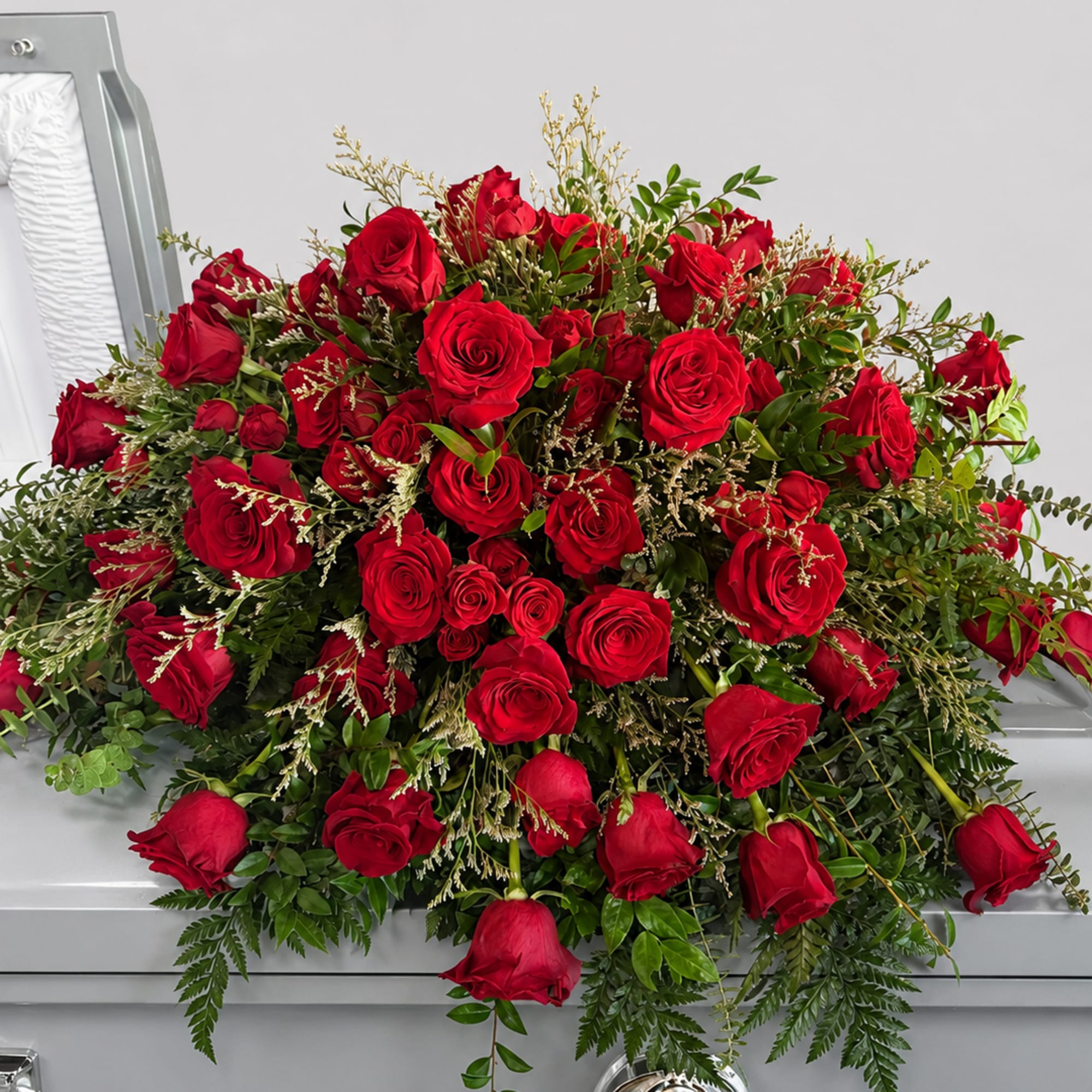 A generous cascade of tightly clustered red roses laid across a silver