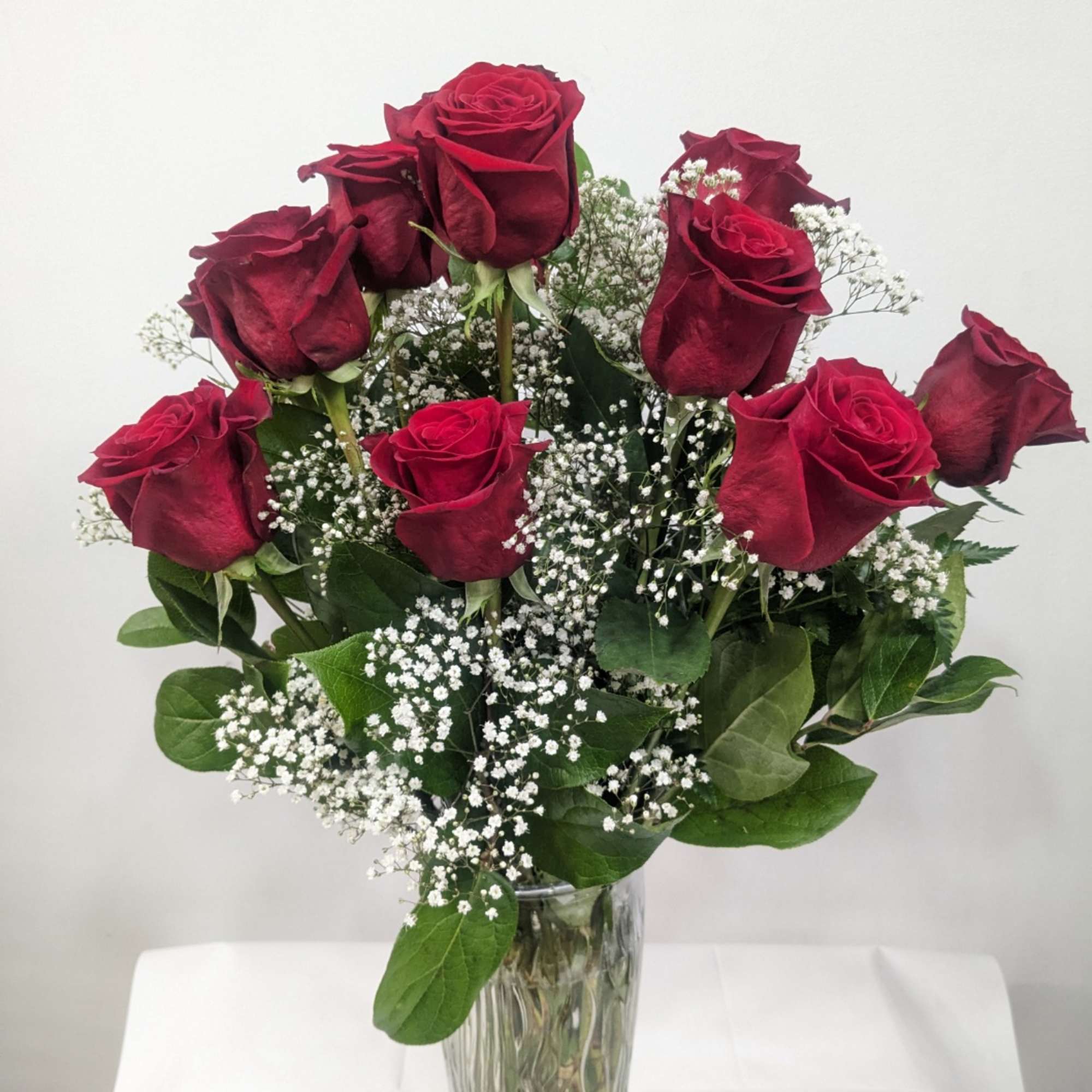 Red roses in a clear glass vase with white baby's breath