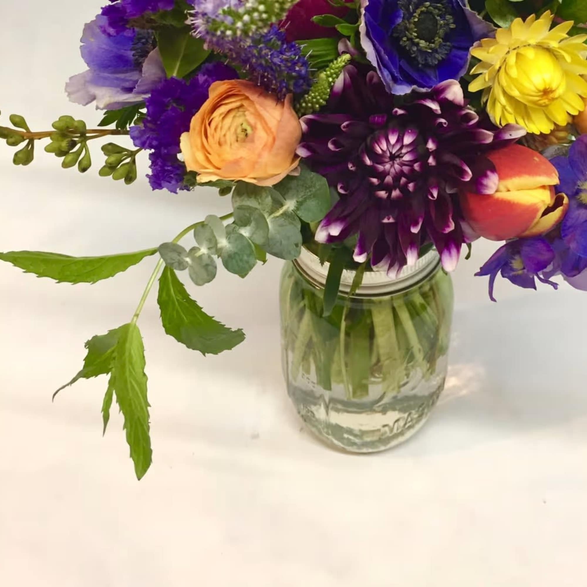 Colorful mixed bouquet in a clear glass jar vase