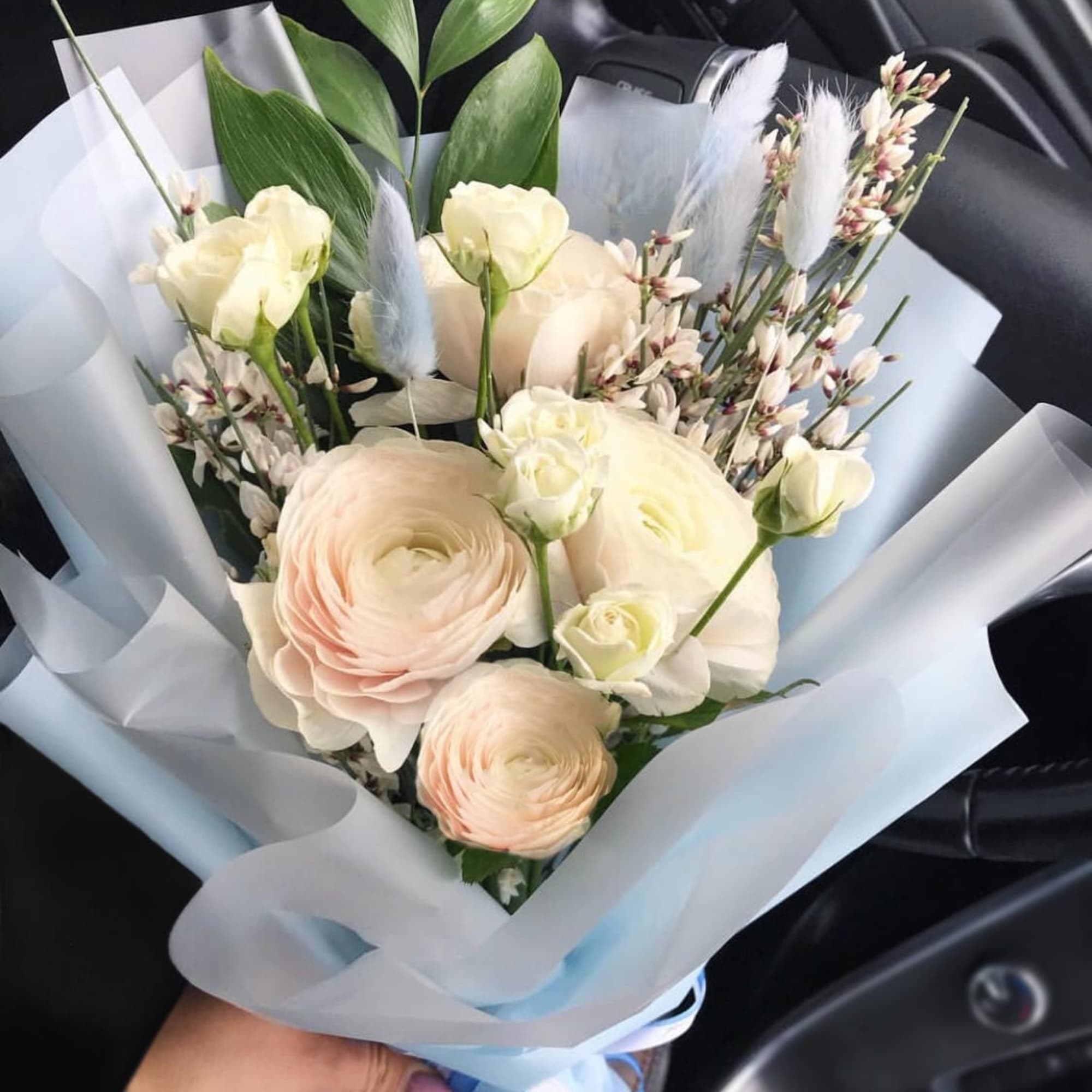 Bouquet of pale cream and blush flowers wrapped in light blue paper