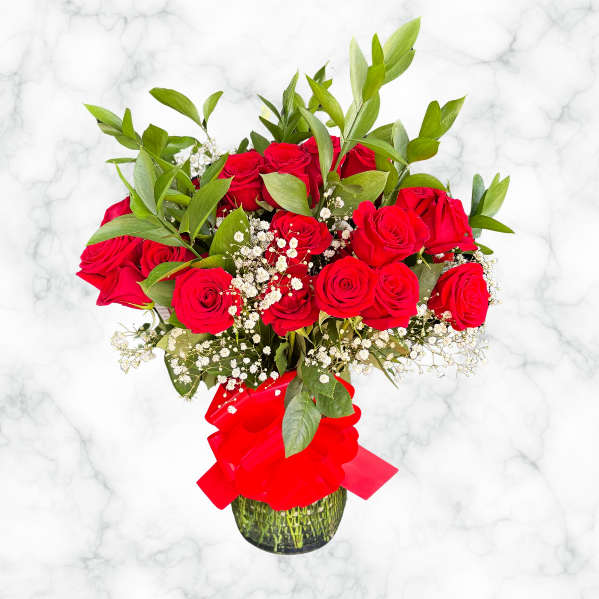 Red roses in a glass vase with baby's breath and a red ribbon