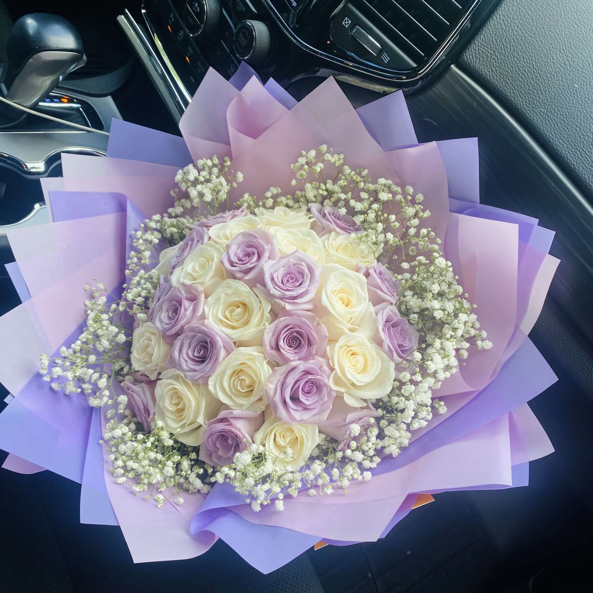 Bouquet of lavender and cream roses wrapped in purple paper