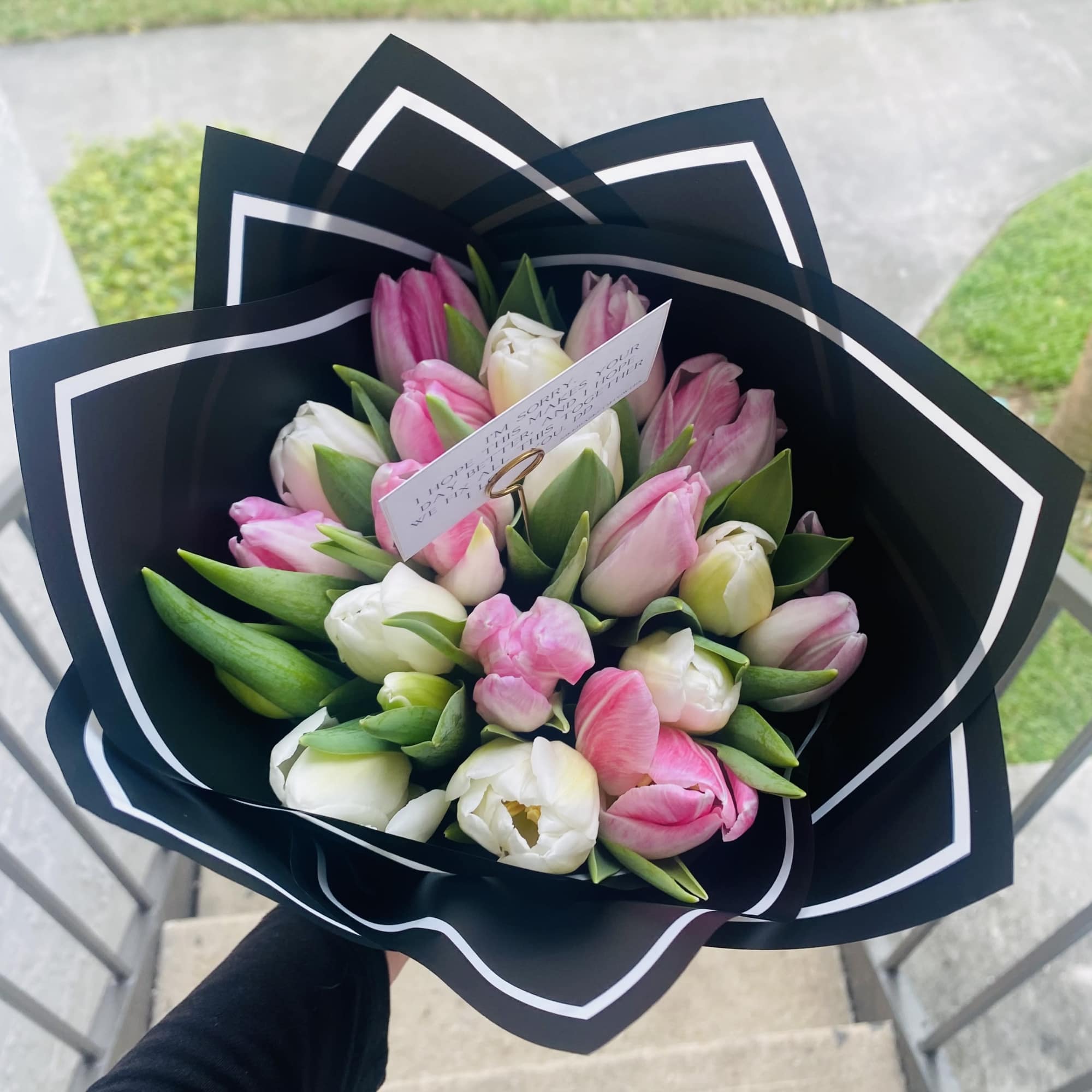 Bouquet of pink and white tulips wrapped in black paper