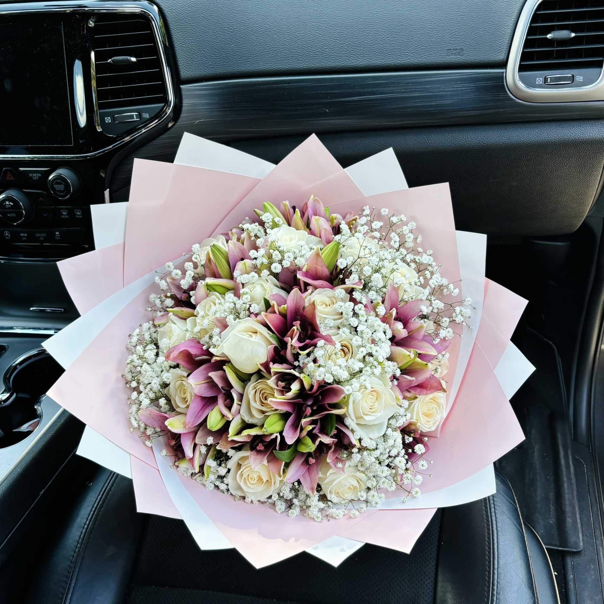 Bouquet of pink lilies and white roses wrapped in pastel paper