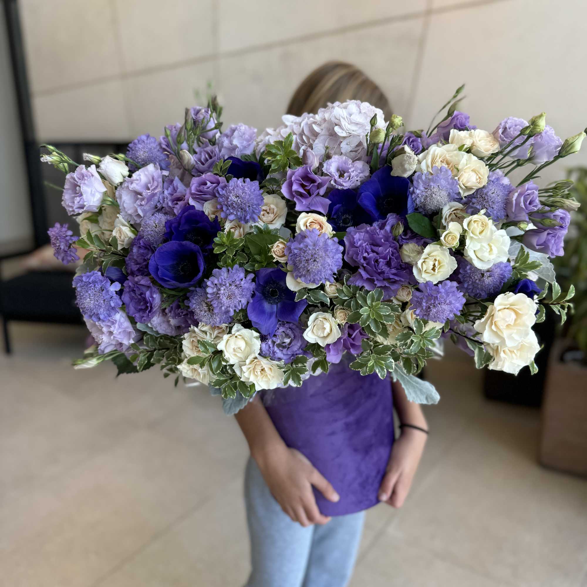 Large bouquet of purple and white flowers wrapped in purple paper